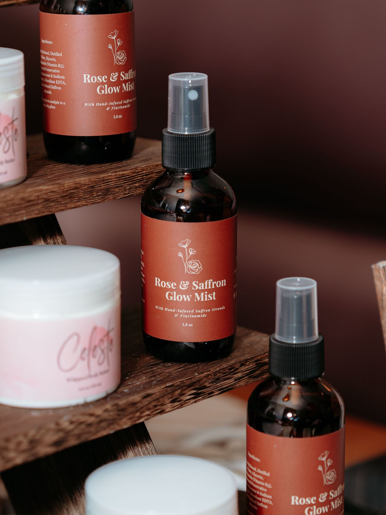 corporate event for tech company in Rose & Saffron Glow Mist facial spray bottles displayed on wooden shelf in amber glass packaging.