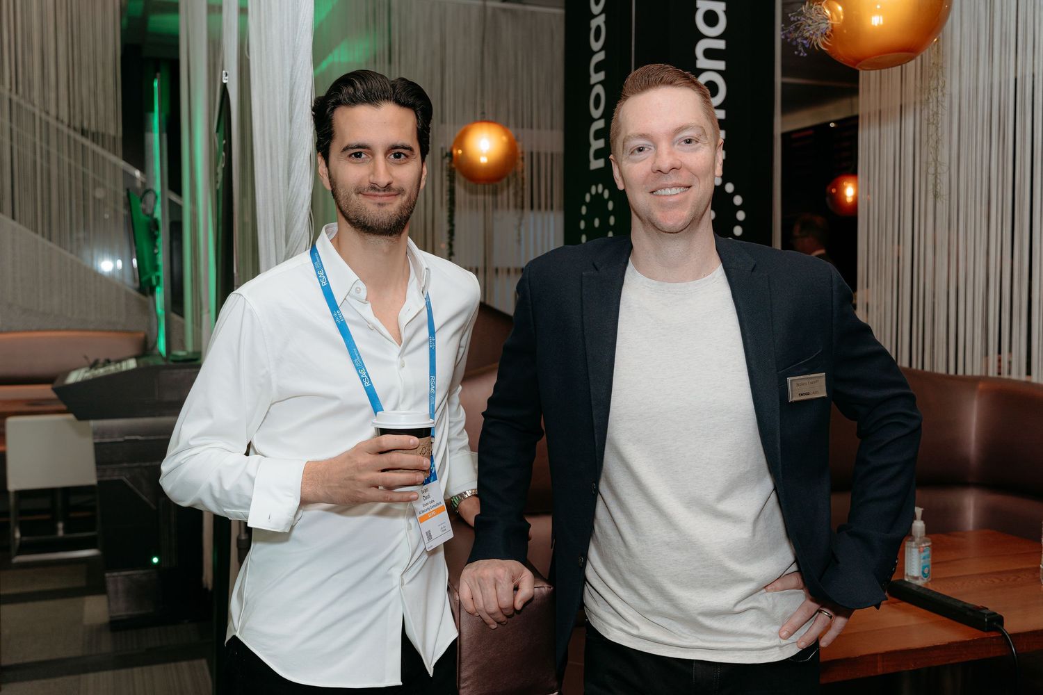Two men smiling and posing together at a corporate networking event in a modern venue.