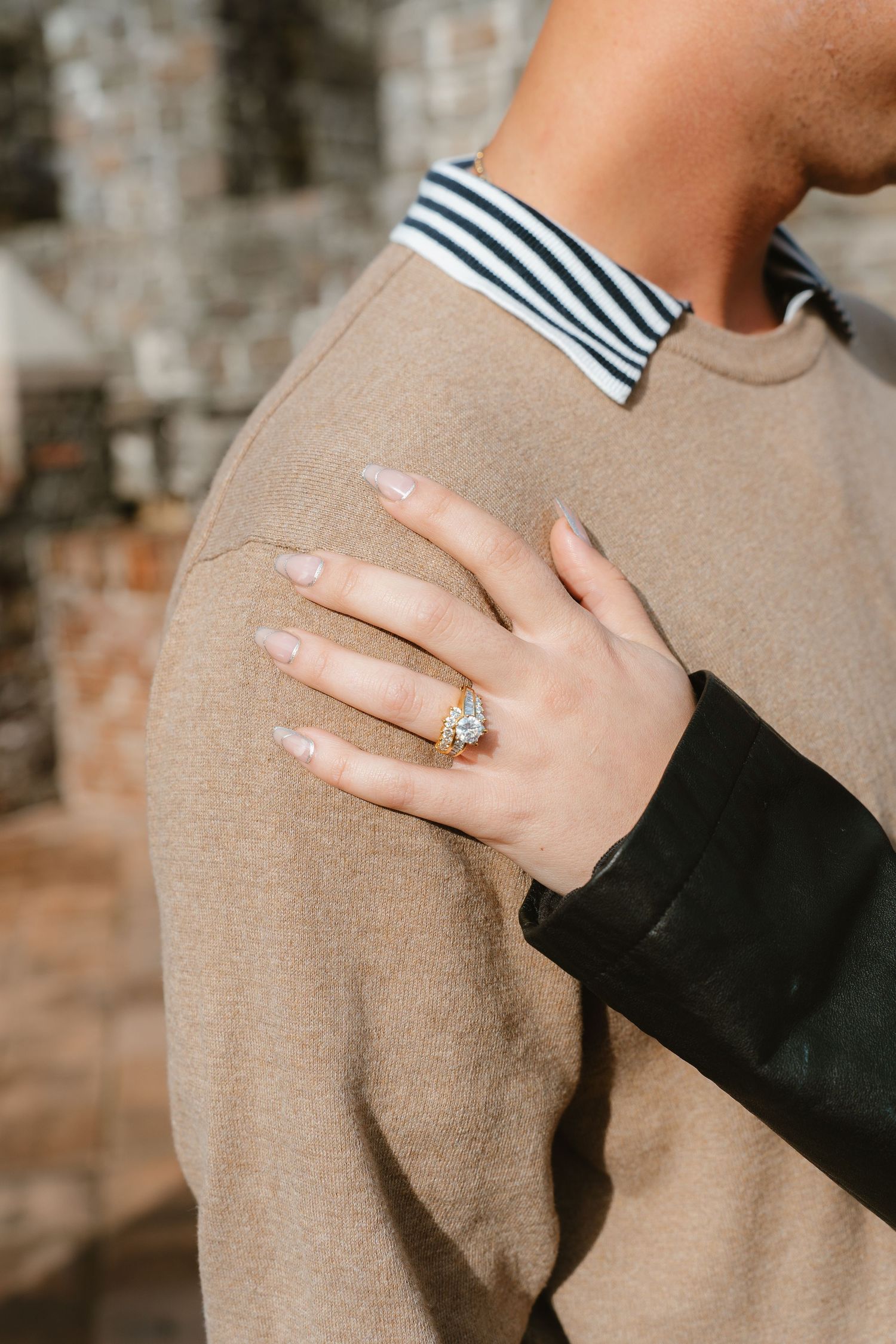 Close-up shots of hands displaying an engagement ring against a beige sweater background.