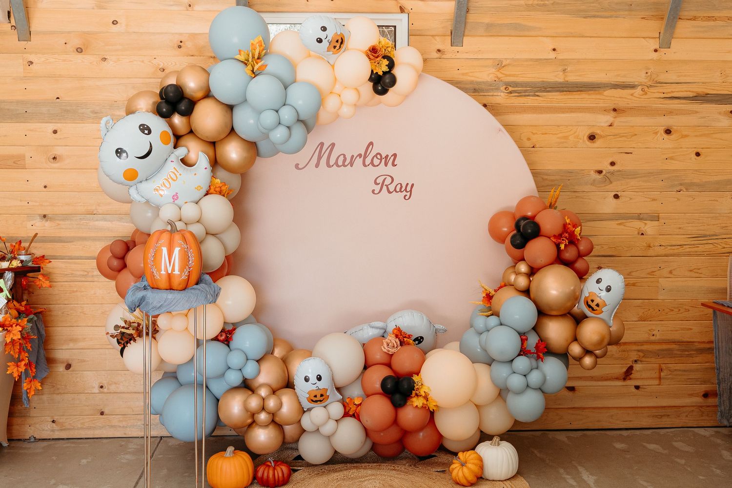 Baby shower balloon arch display with blue, orange and cream balloons spelling Marlon Ray.