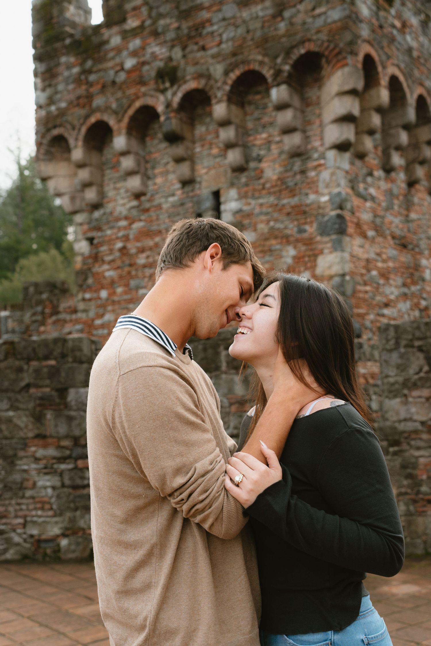 A couple shares an intimate moment in front of an ancient stone castle wall in Napa Valley winery