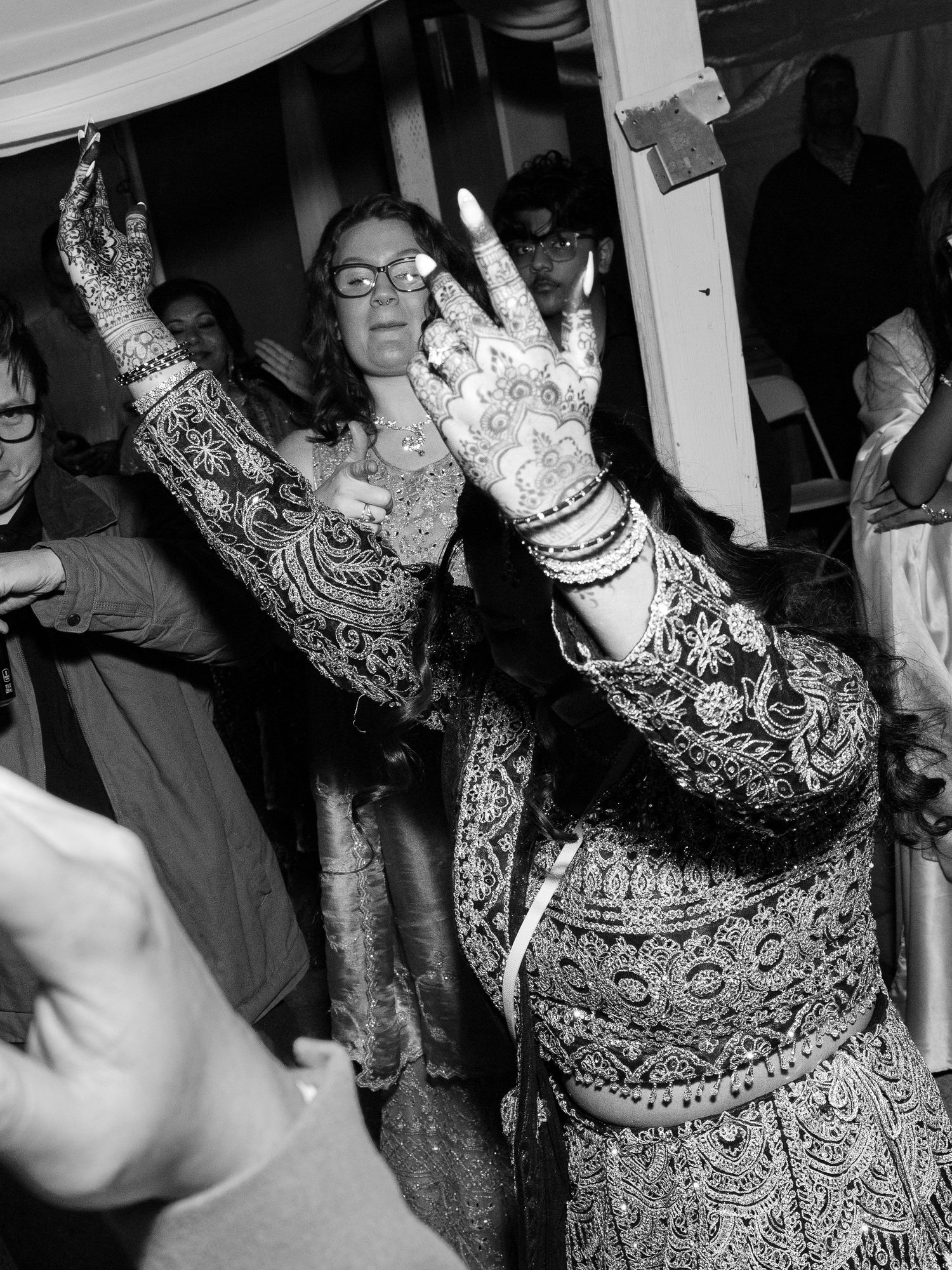 Sacramento engagement bride with intricate henna mehndi on her hands dancing at a wedding celebration in traditional embroidered attire.