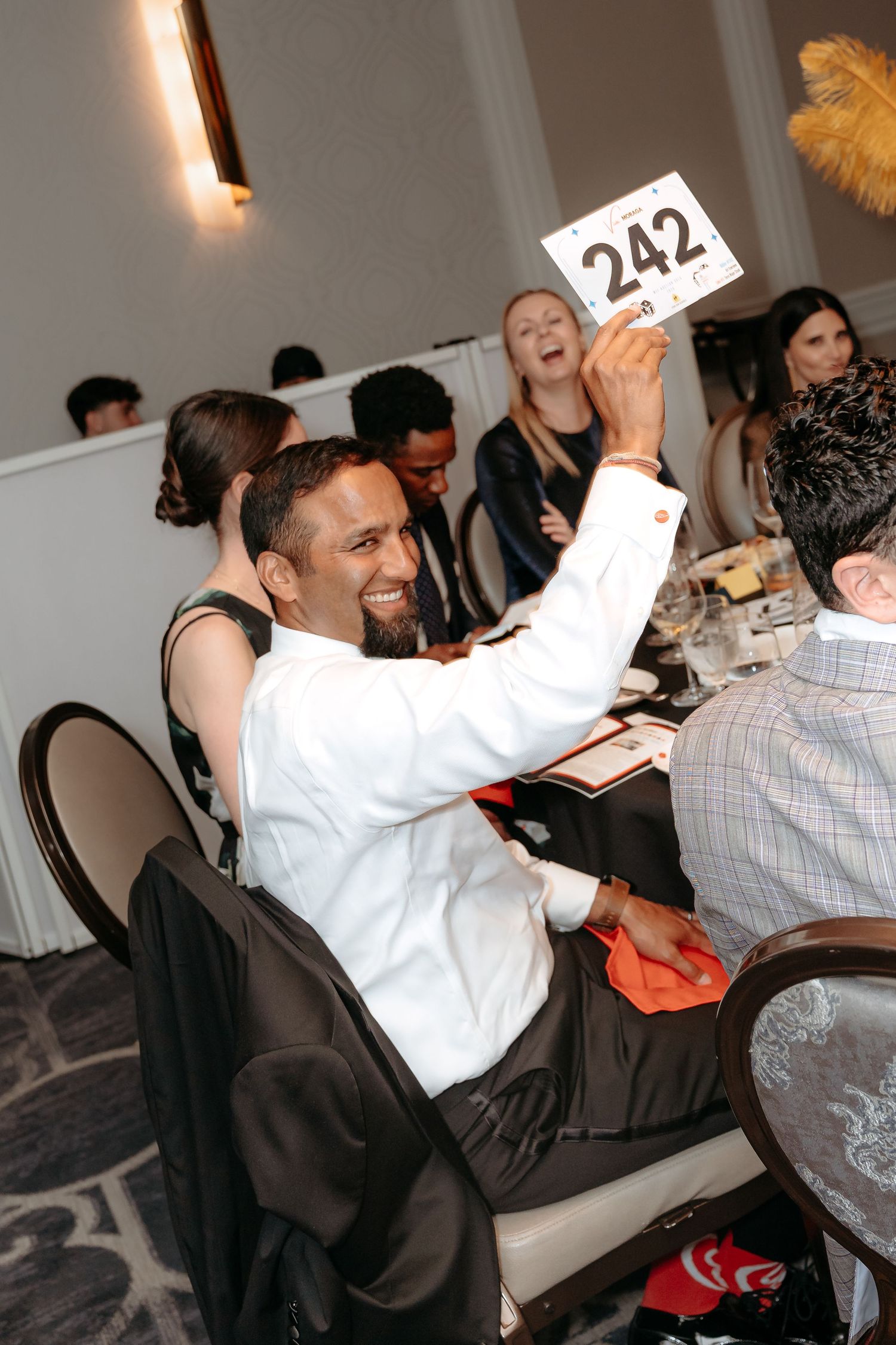 Corporate non profit event  where silent auction Guests at a formal dinner event raise their hands in celebration.