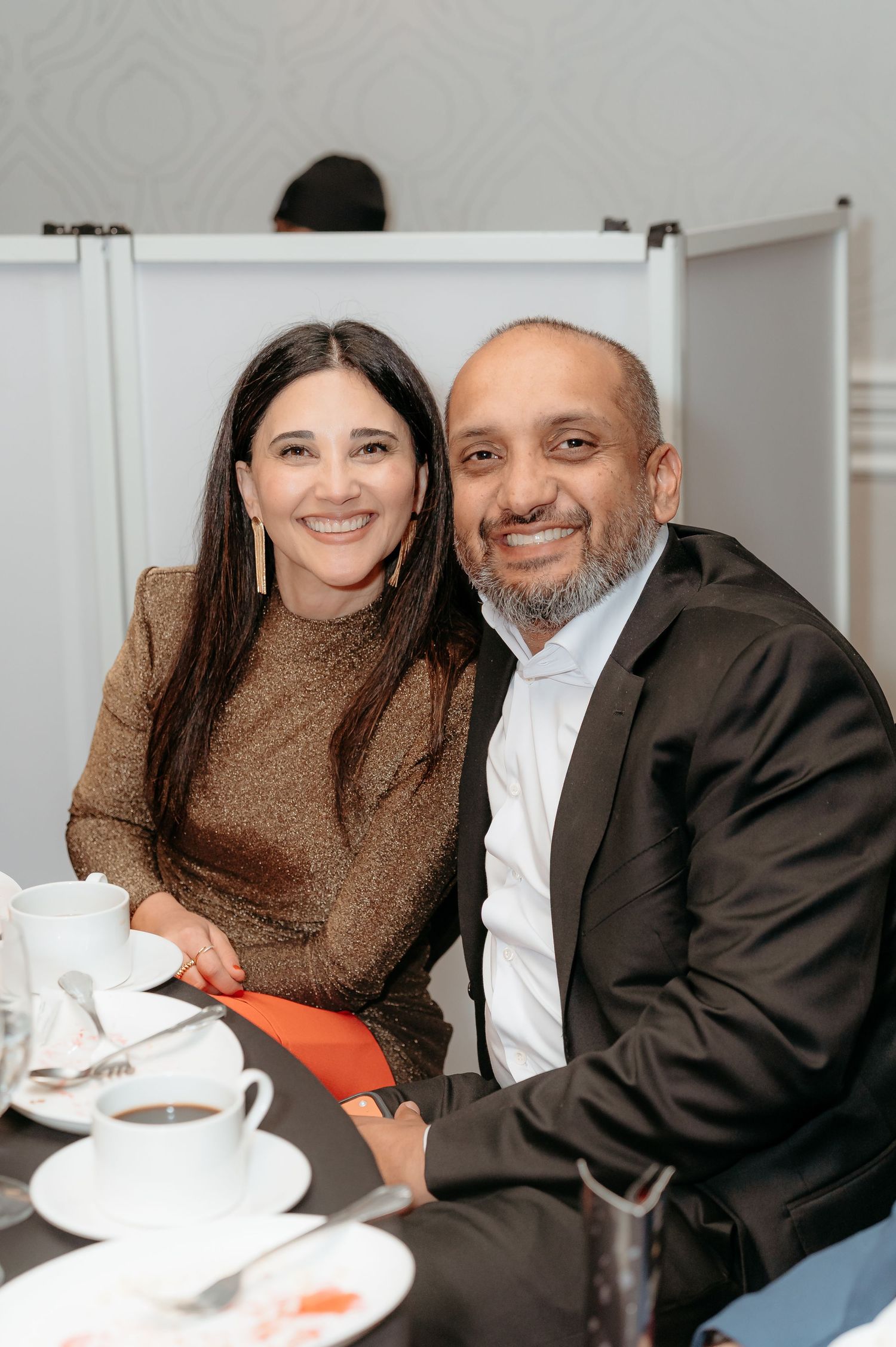 Corporate non profit event  where Two guests share a warm moment at a tea service with white teapots on the table.