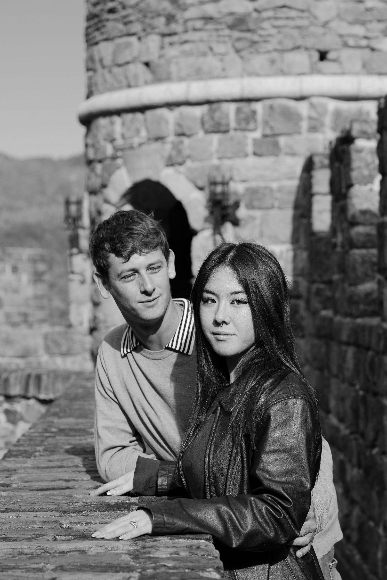 A couple leans against a stone wall in a series of vintage black and white photographs.