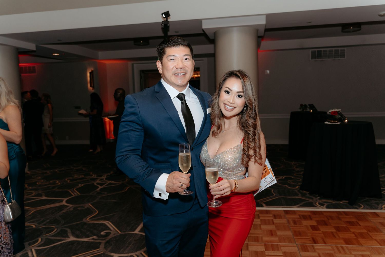 Couples in formal attire dancing and celebrating at an elegant event with champagne glasses.