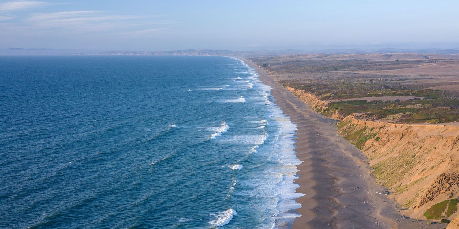 Aerial view of Point Reyes National Seashore with long sandy beach and coastal cliffs in California.