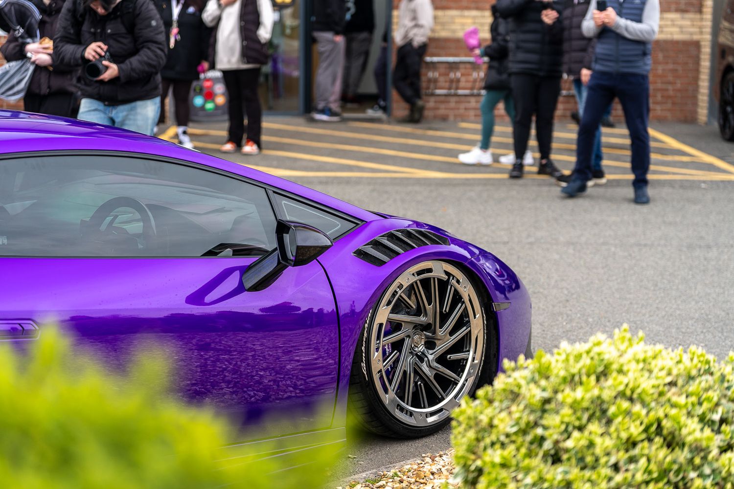 Stunning purple Lamborghini Huracan supercar at a car meet surrounded by onlookers.