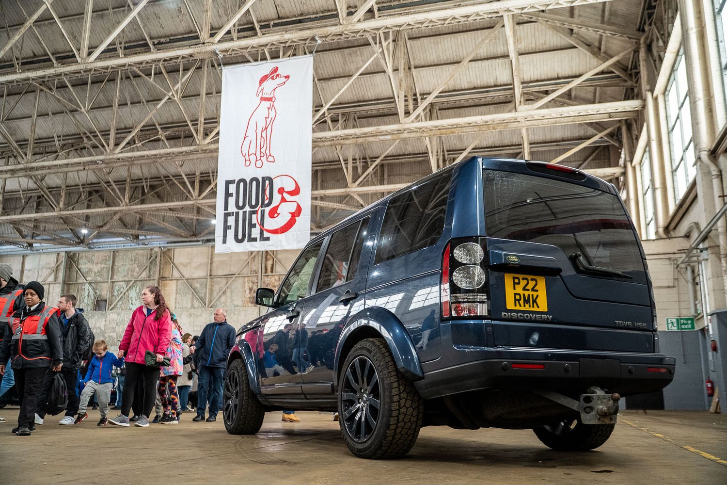Dark blue Land Rover Discovery parked inside a hangar near a Food and Fuel banner.
