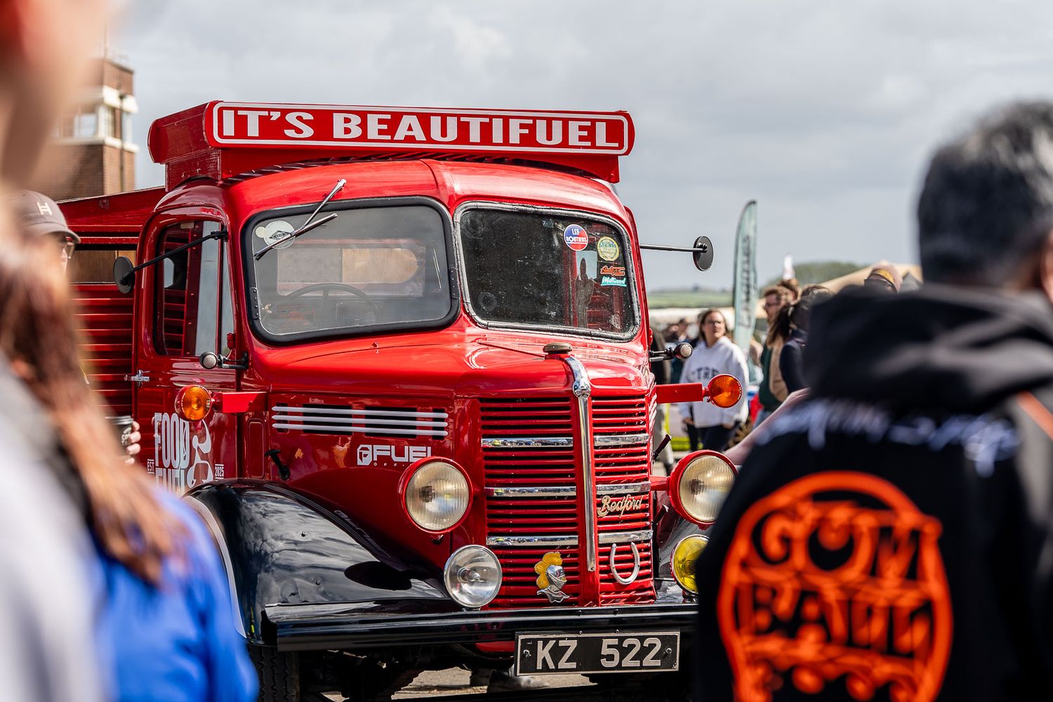 Vintage red Bedford truck with It's Beautifuel slogan at a classic vehicle show.