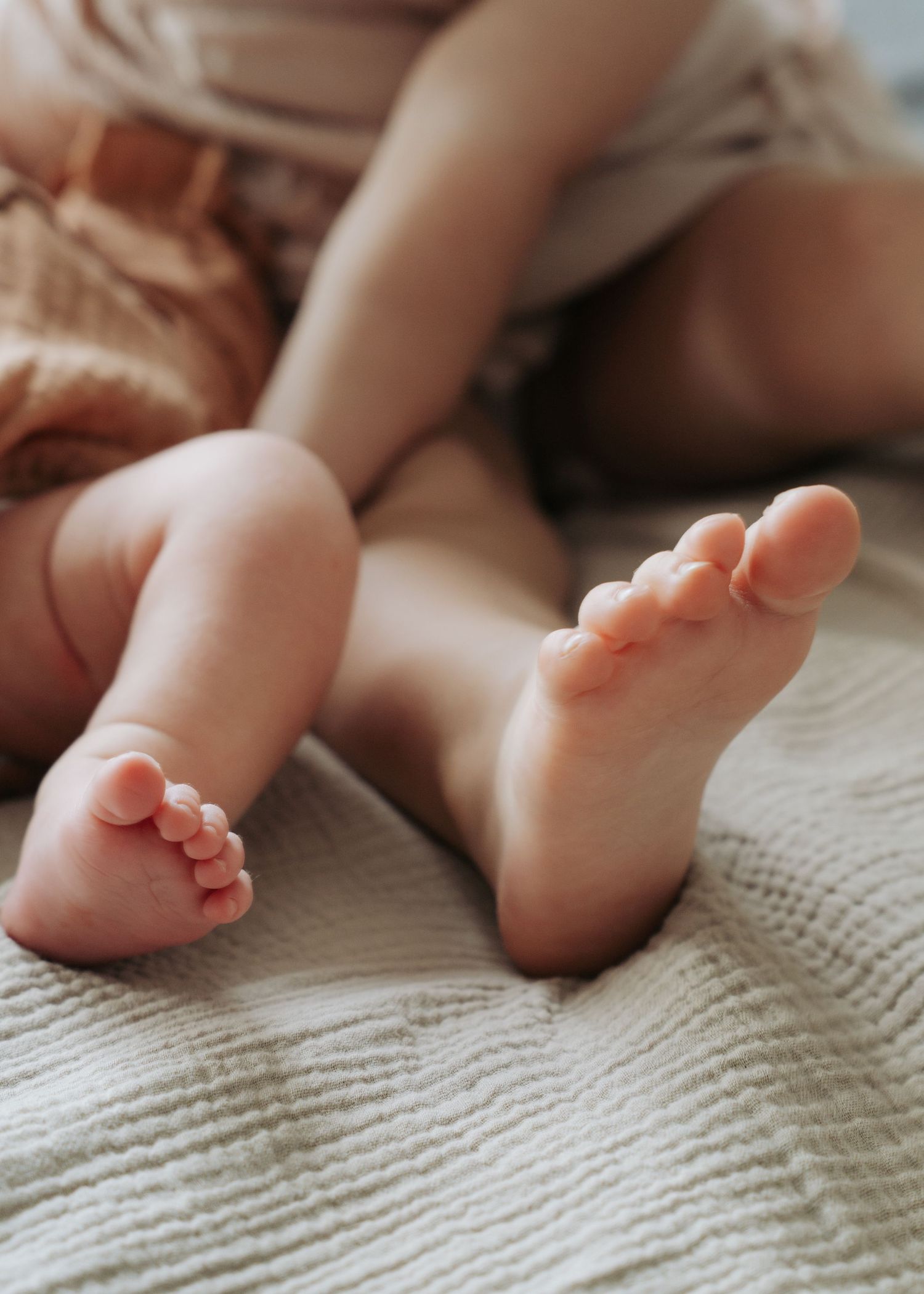 Close-up of tiny newborn baby feet resting on a soft white knit blanket.