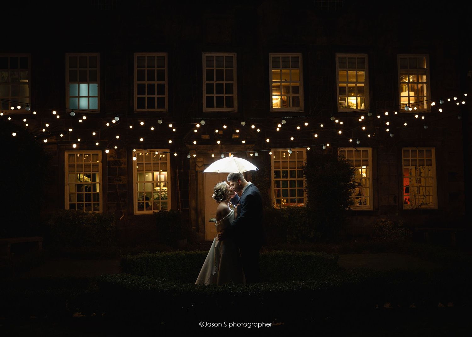 Off-camera flash portrait of the bride and groom looking at each other in front of their wedding venue.