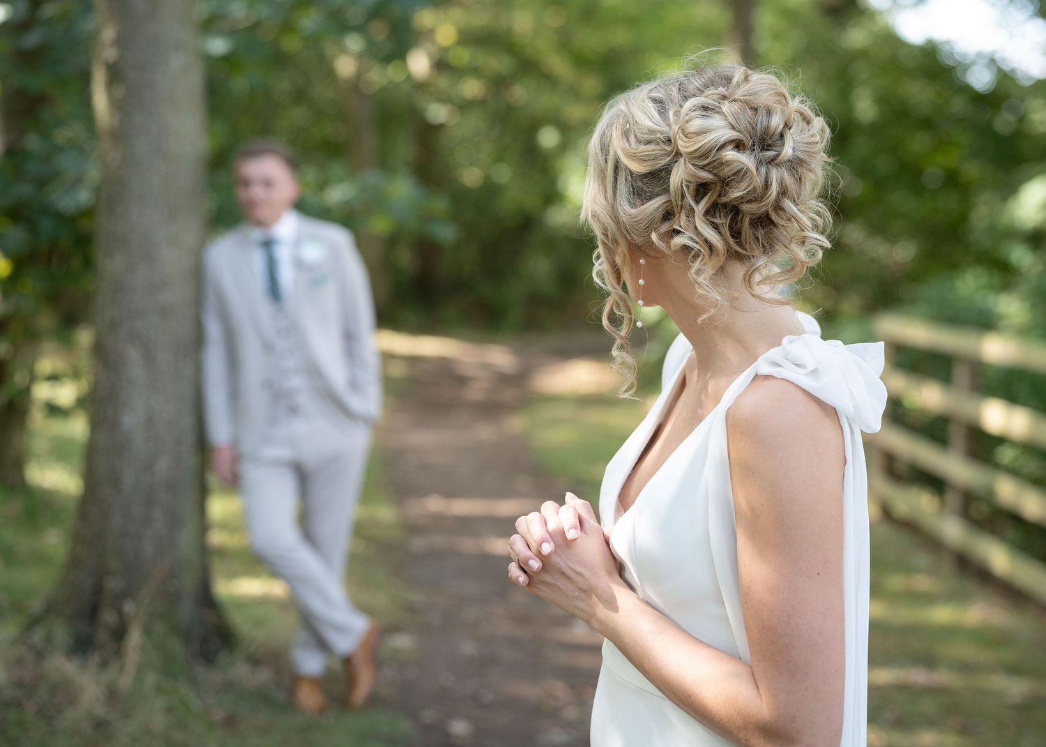 Bride looking at the groom as he's posing for his solo shoot