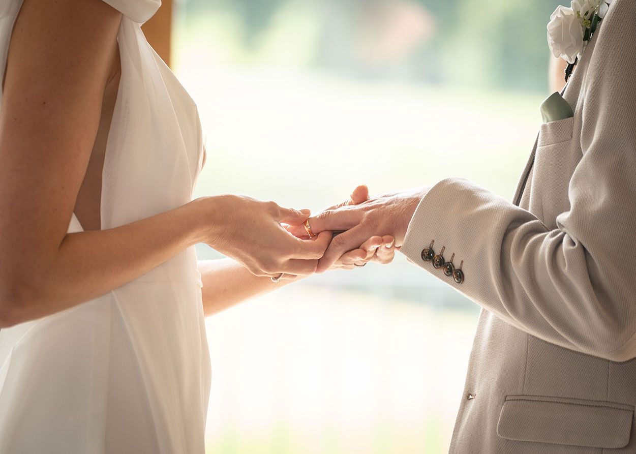 Close-up of the wedding ring being placed onto the groom’s finger during the ceremony.