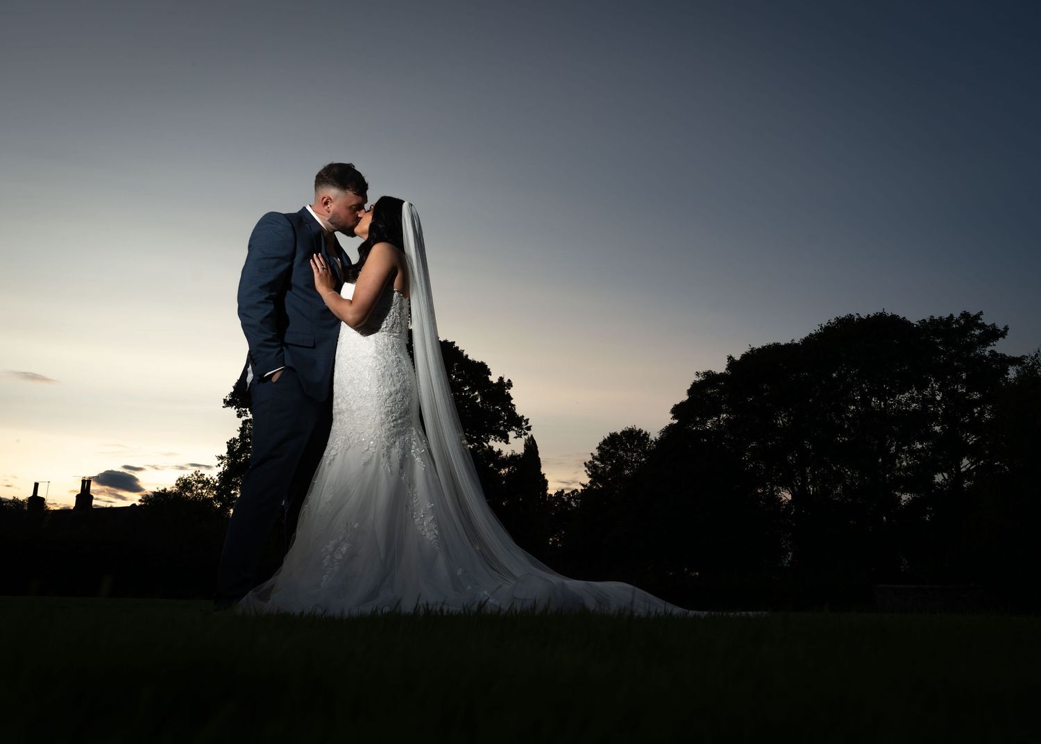 Off-camera flash portrait of the bride and groom looking at each other during sunset.