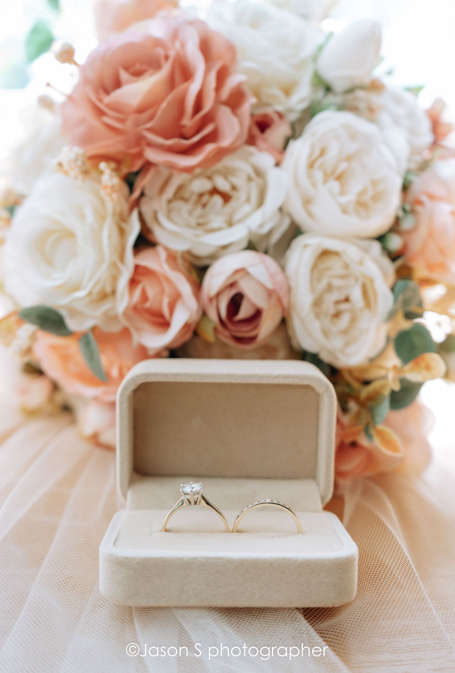 Detailed close-up of the wedding rings with the bride’s bouquet softly blurred in the background.