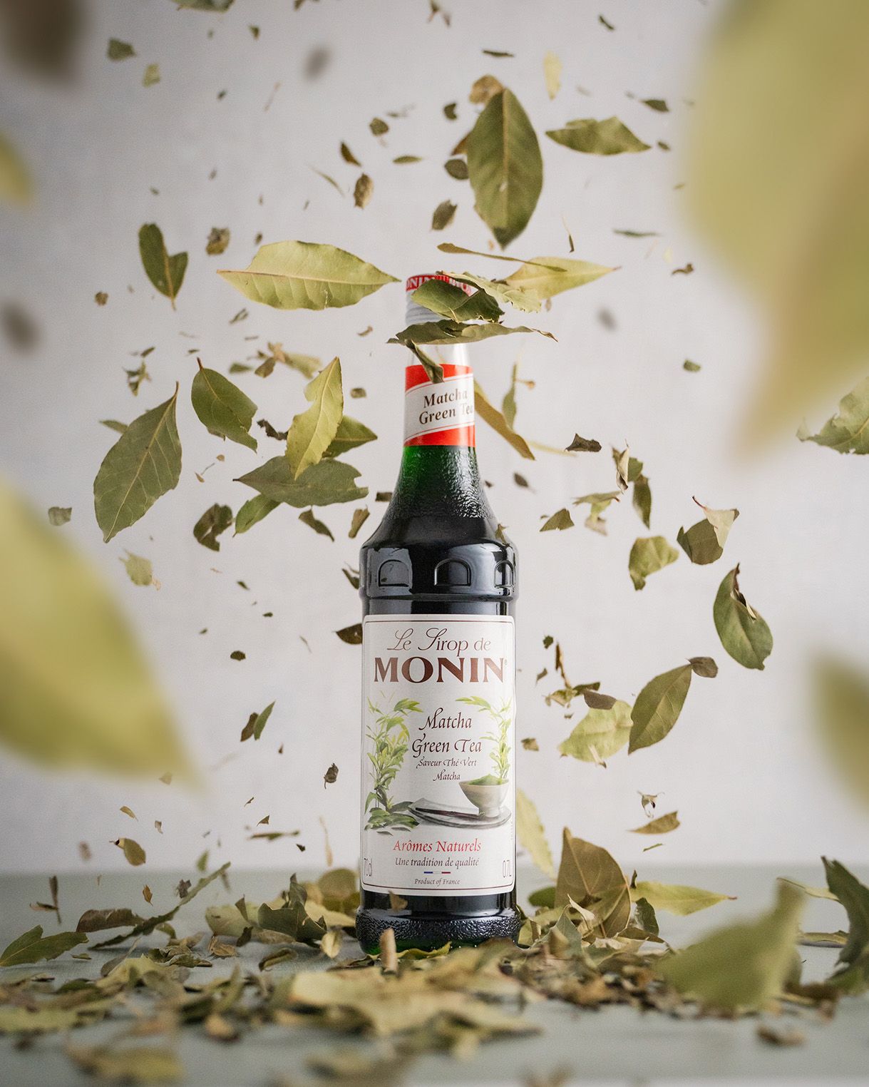 leaves falling around a Monin matcha bottle