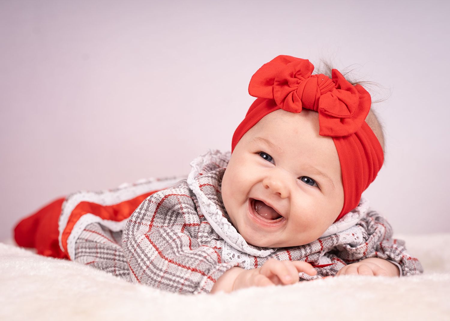 A full body shot of a baby laying down looking at the camera
