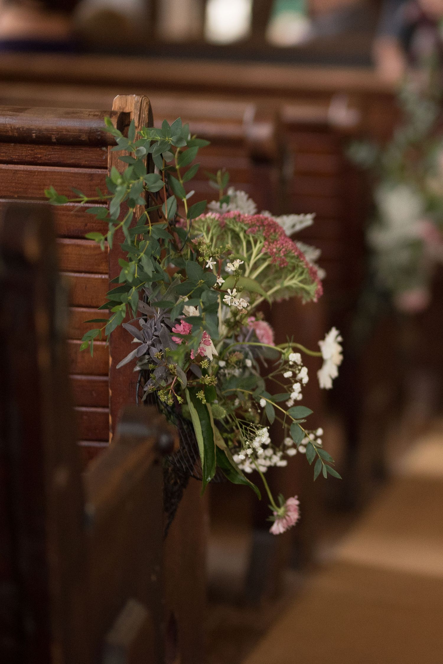Fresh wildflower arrangements decorating church pews for a wedding ceremony.