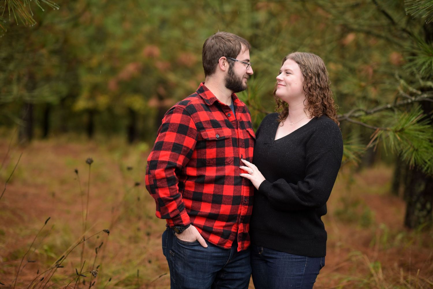 A couple poses playfully together against a natural forest backdrop.