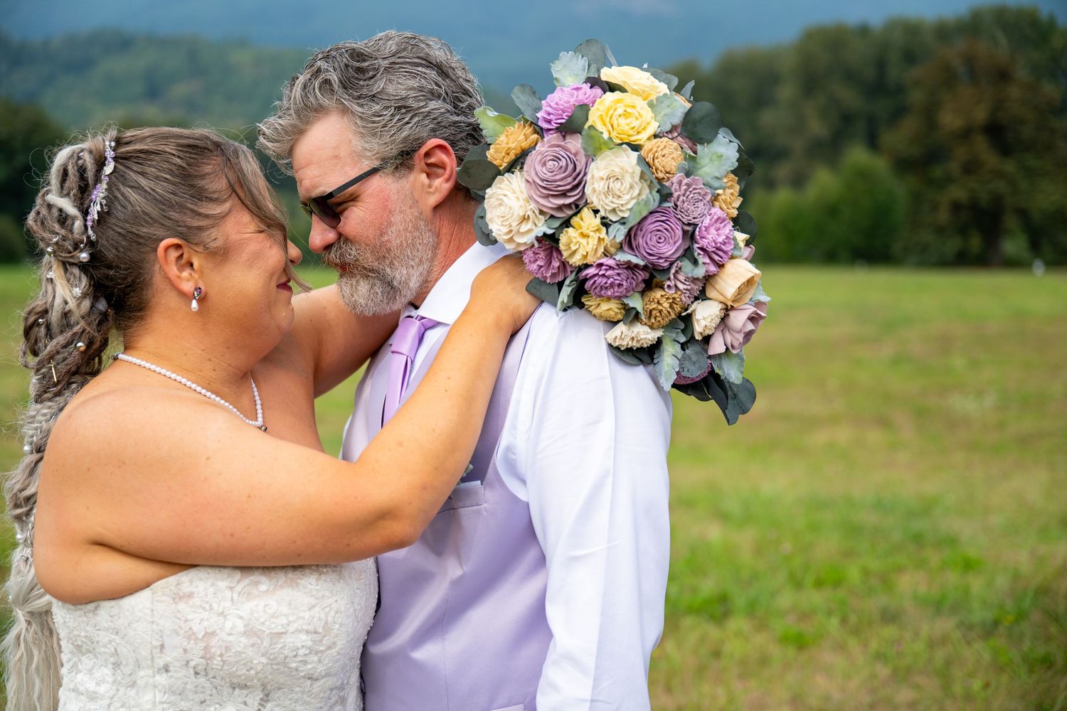 Close-up of couple with colorful wedding bouquet in mountain setting.