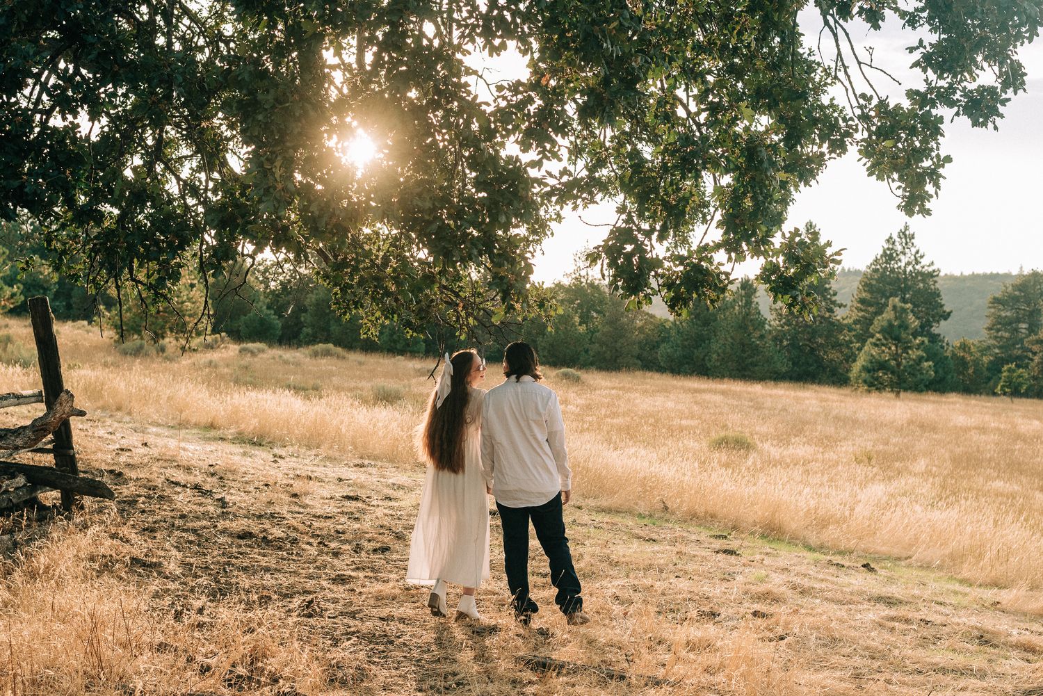 Couple explores a sun-dappled hillside during golden hour.