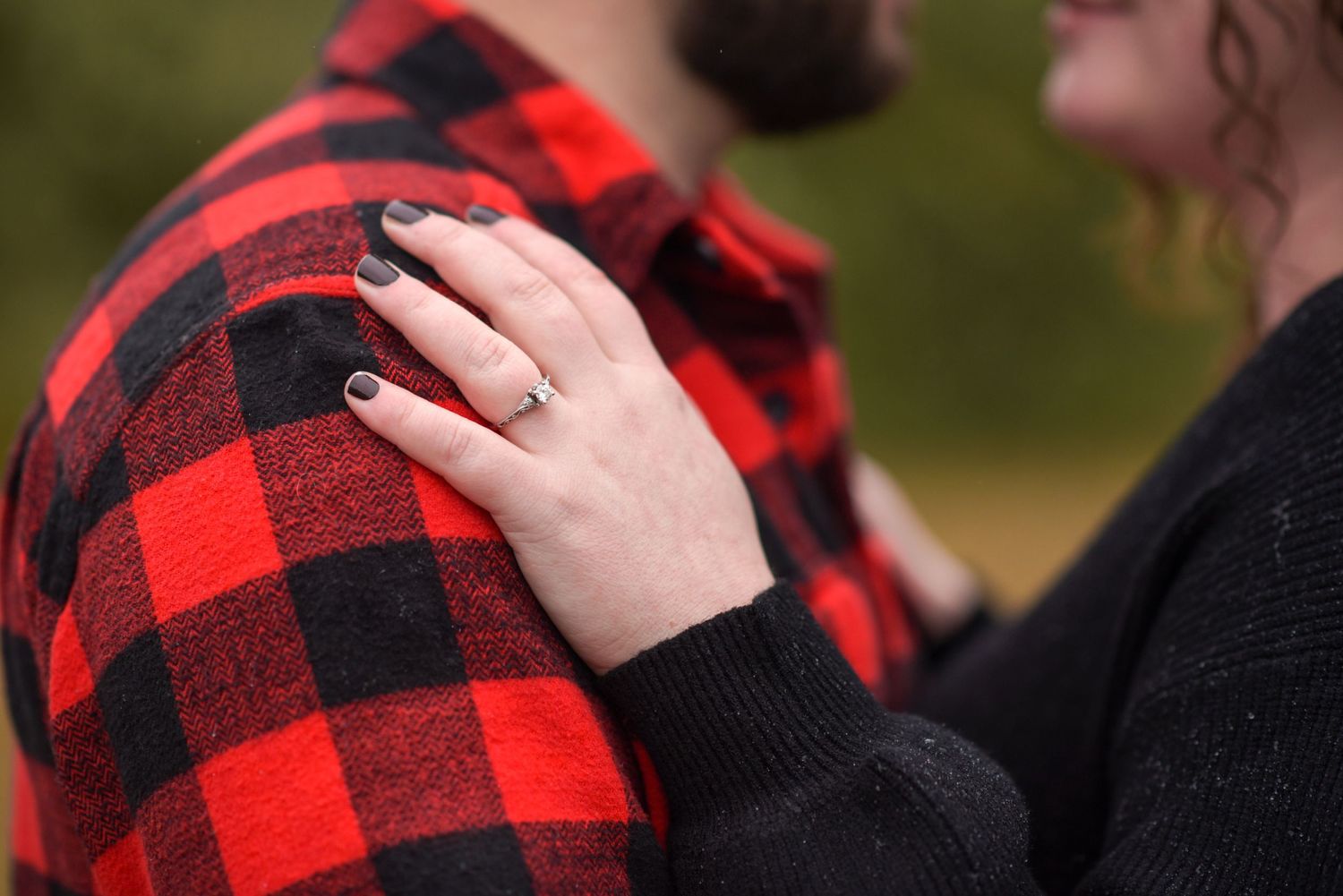 Close-up detail of red buffalo plaid flannel and black sweater.