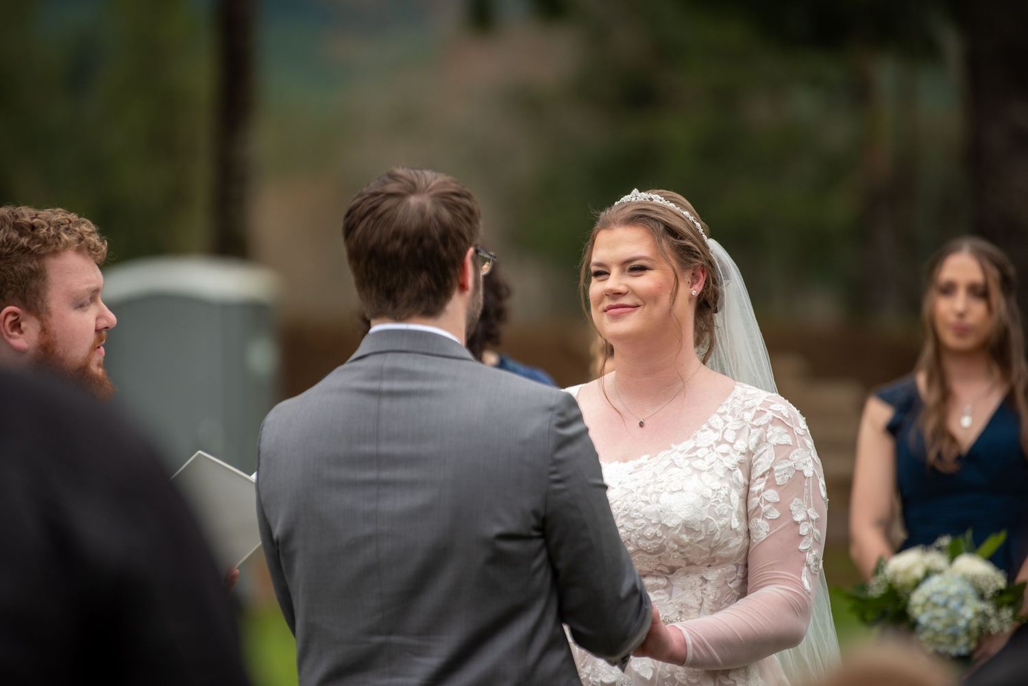 Outdoor wedding ceremony with wooden hexagonal arch and floral decorations.