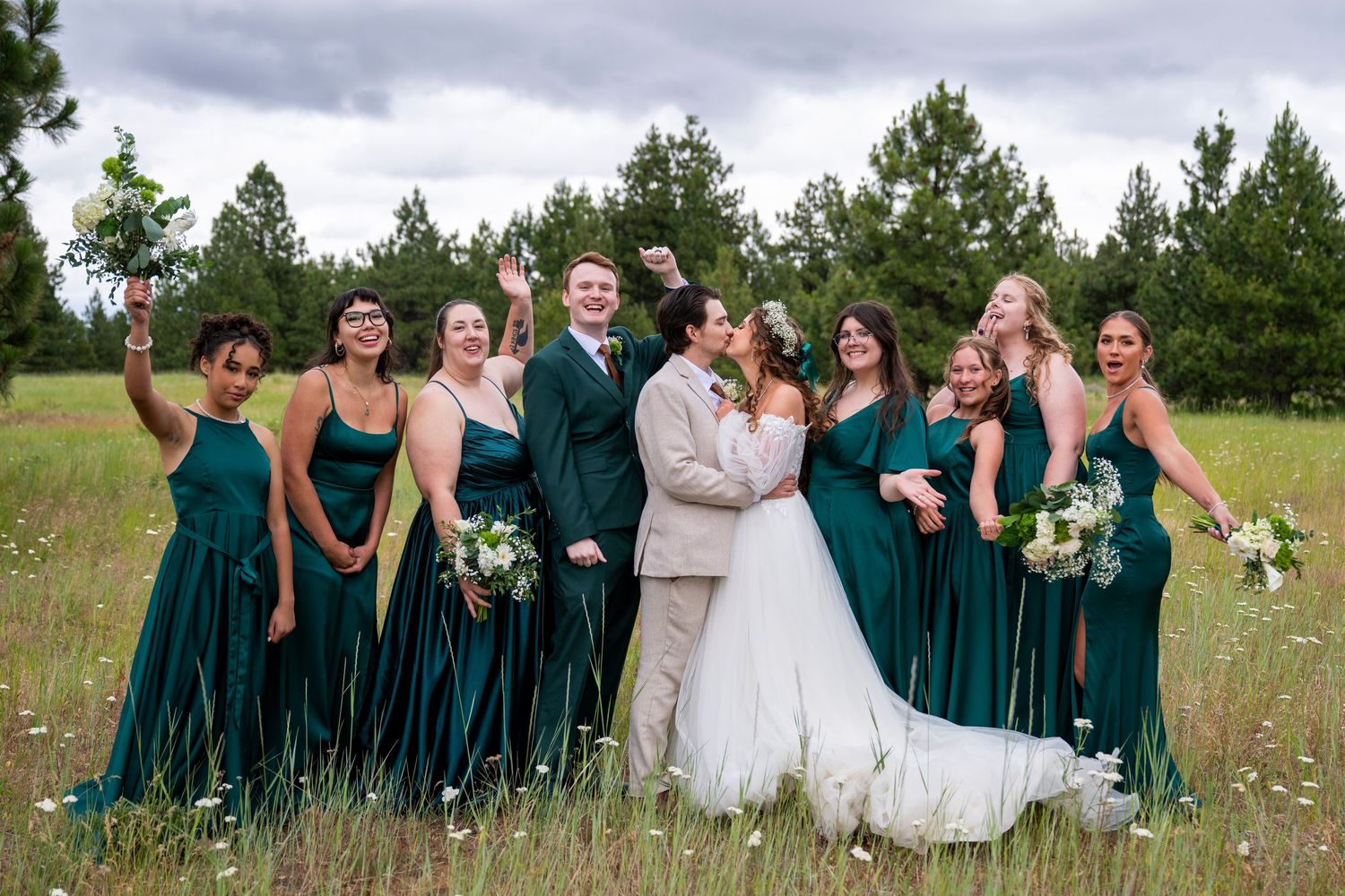Bride and groom kiss while bridesmaids cheer at their wedding in the dalles, oregon