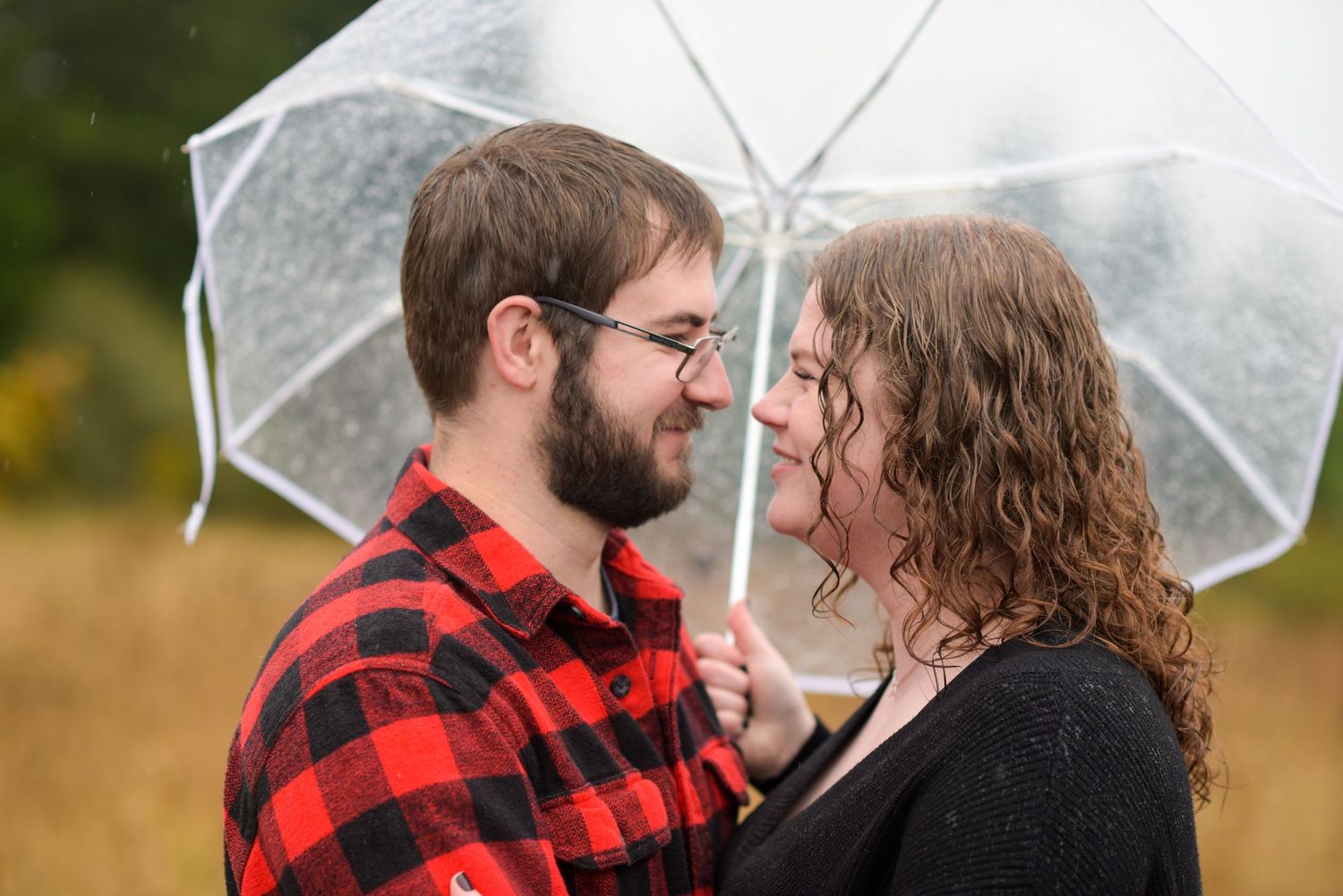 Couple sharing an intimate moment under a clear umbrella in autumn.