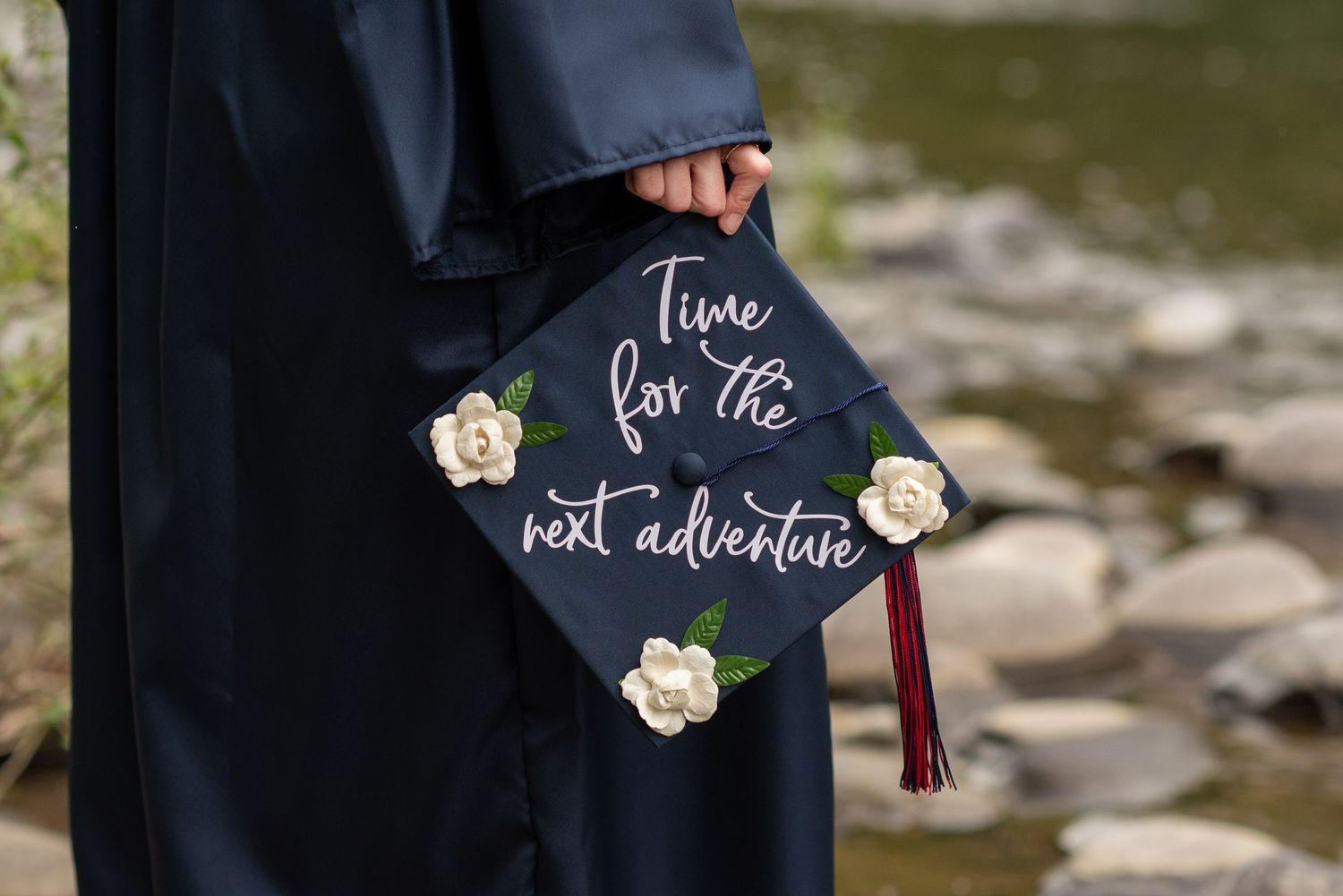 Graduation cap decorated with white flowers and the phrase Time for the next adventure.