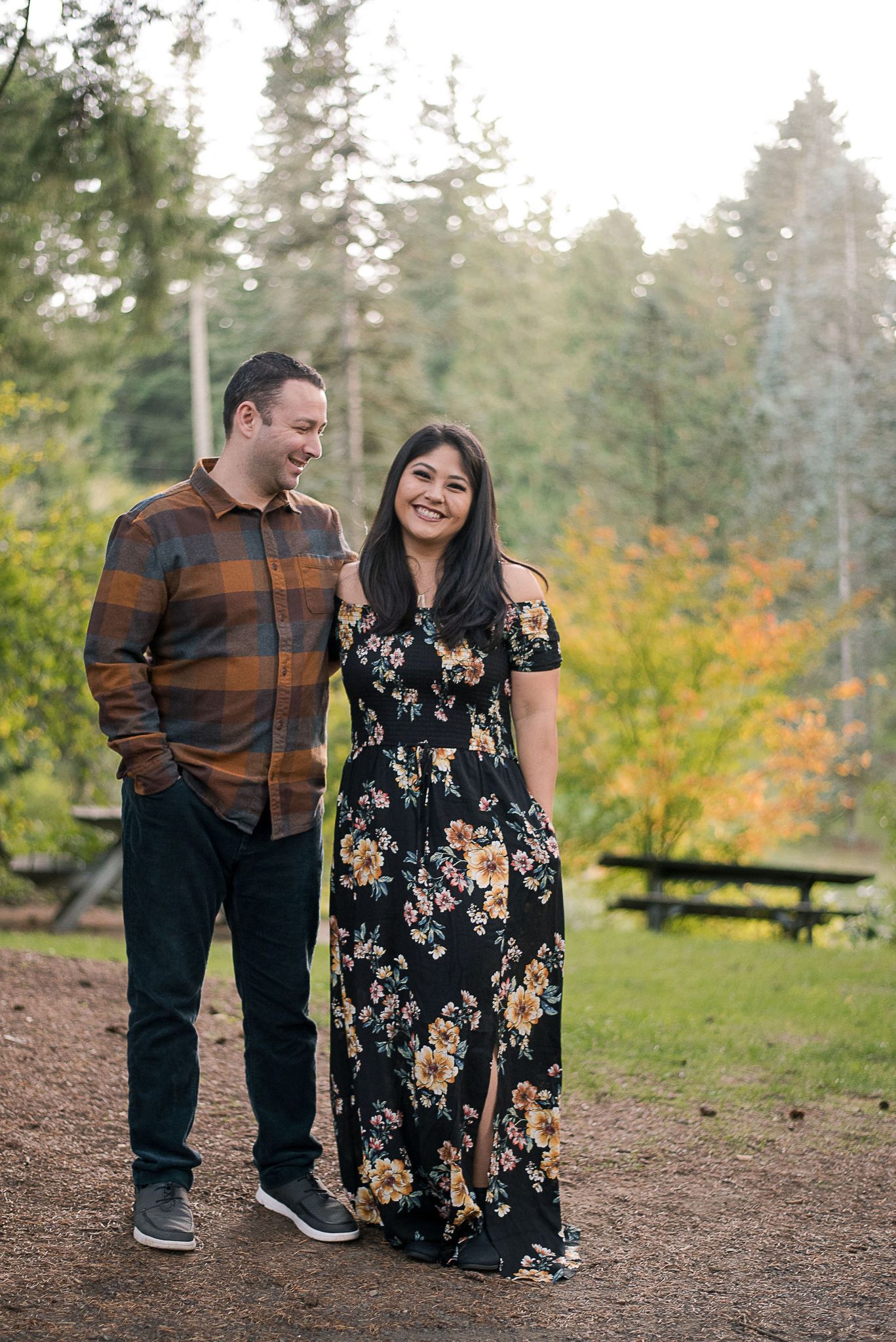 Couple sitting together on forest trail sharing intimate moment in casual fall attire.