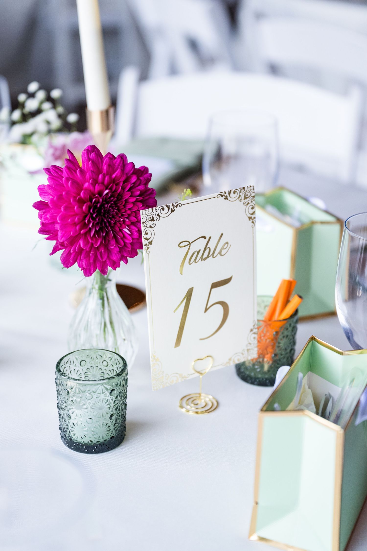 Elegant wedding table setting featuring a gold-framed Table 15 card beside a vibrant magenta dahlia centerpiece.