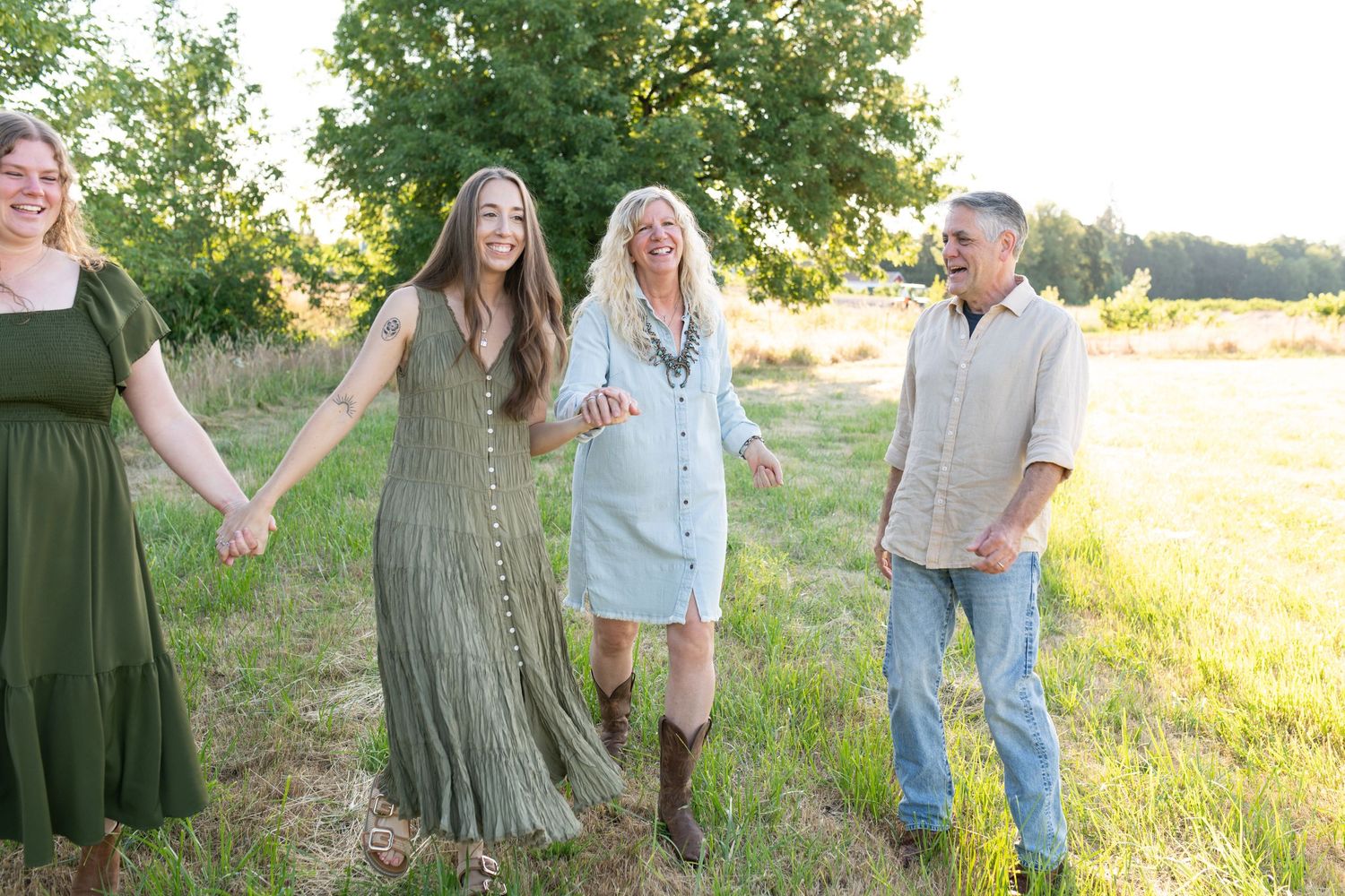 Joyful family of four walking hand in hand through golden sunlit meadow together.