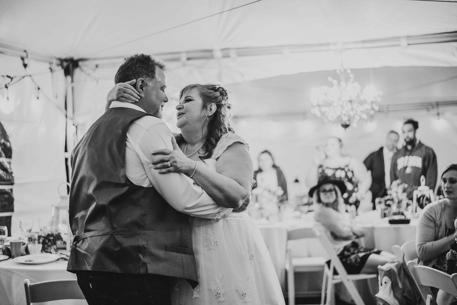 Couples dancing together at an indoor wedding reception under a white tent.