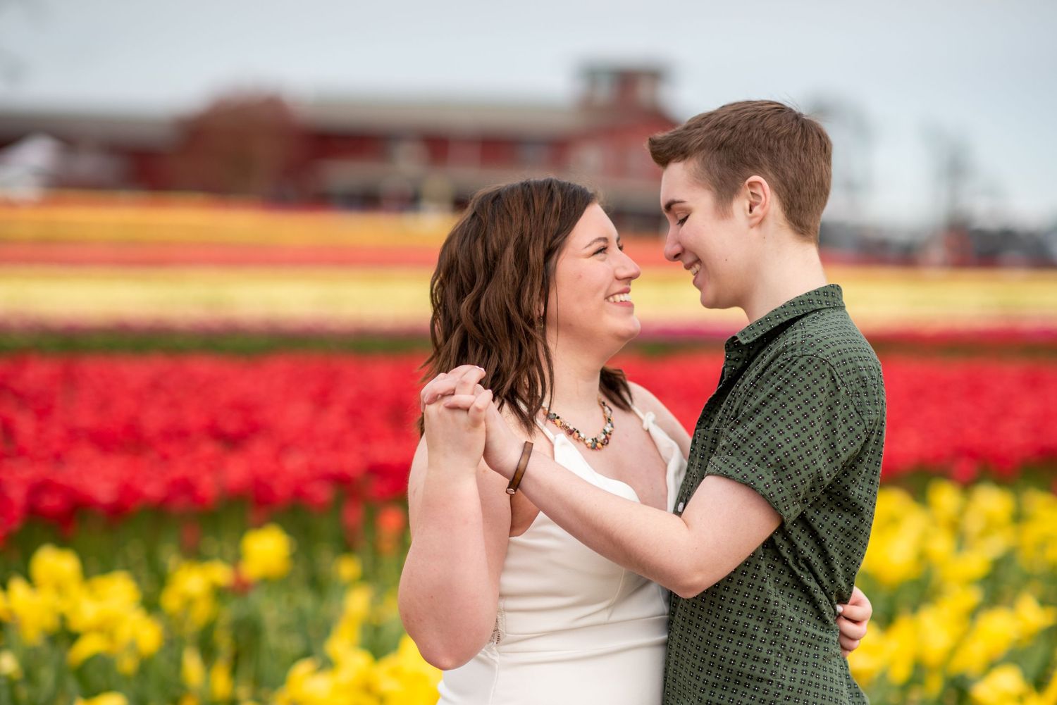 Couple shares tender moment among colorful tulip fields during spring.