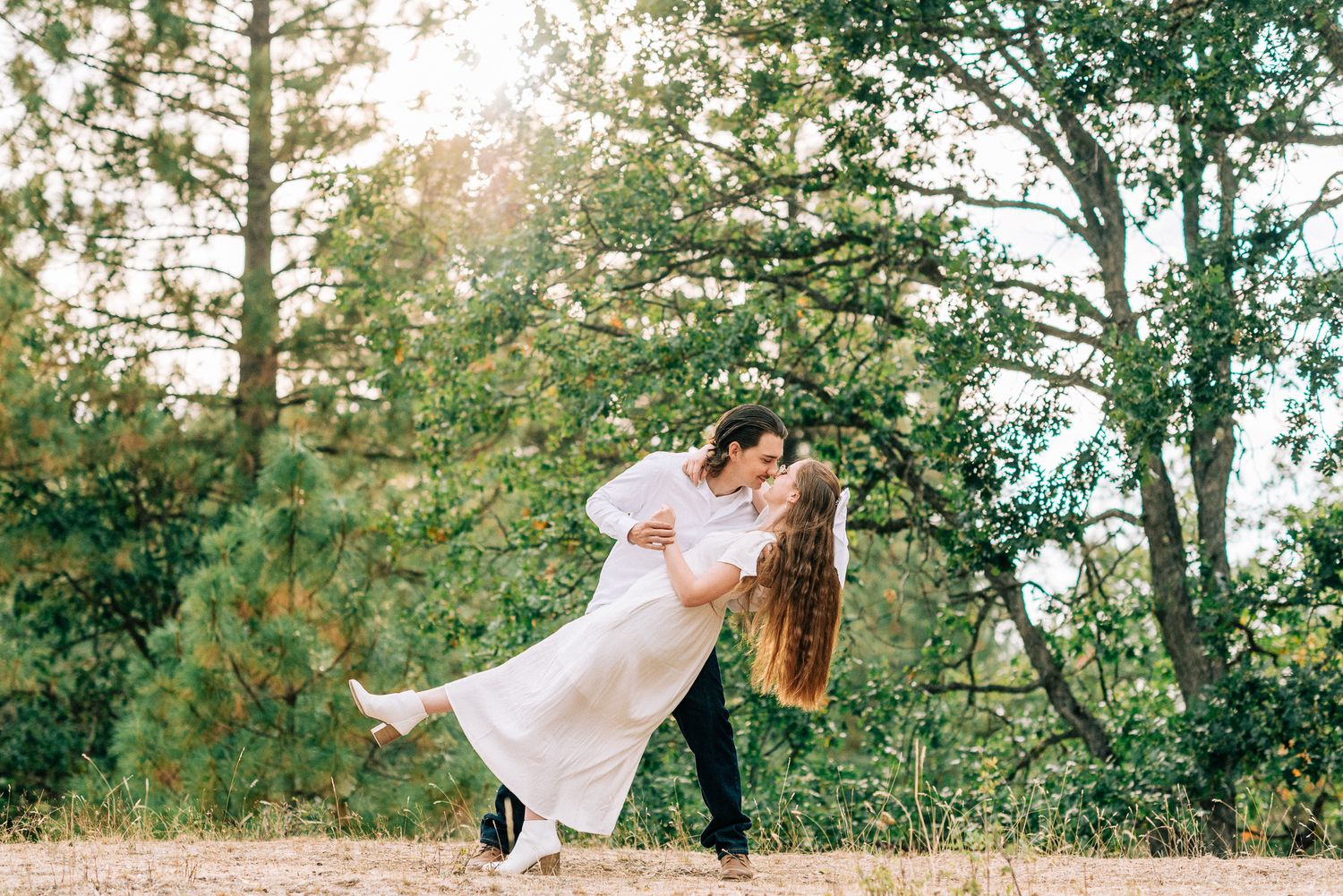 A groom dips his bride dramatically in a romantic outdoor forest photo session.