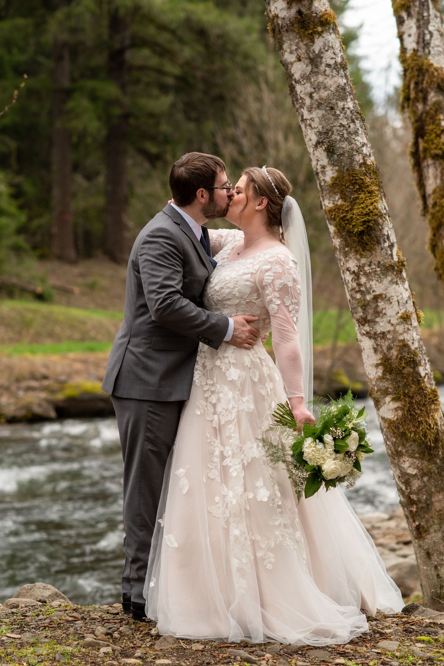 Intimate wedding portraits by a rushing stream with birch trees in the background.