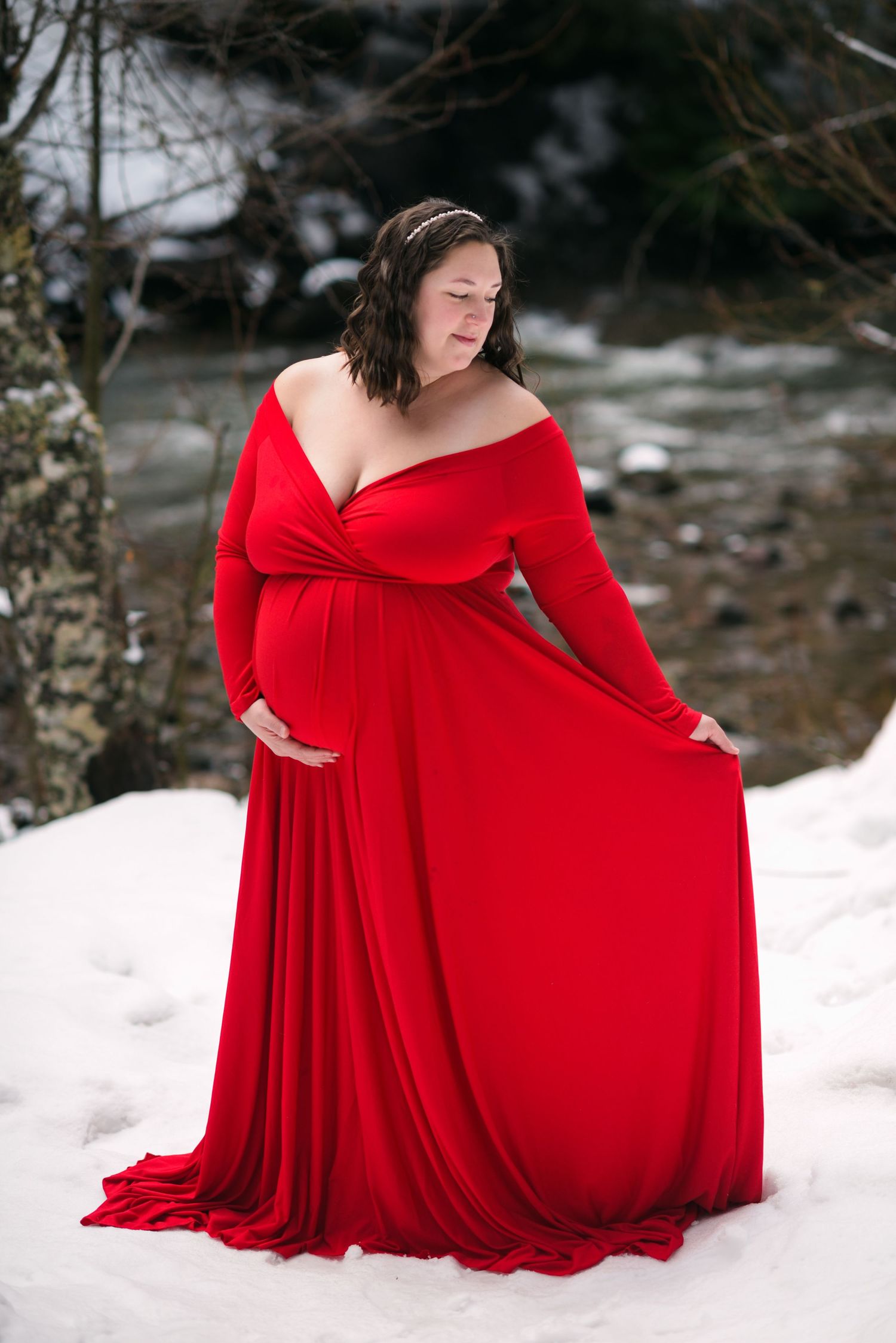 A flowing red dress creates dramatic contrast against snowy winter ground in a series of elegant poses.