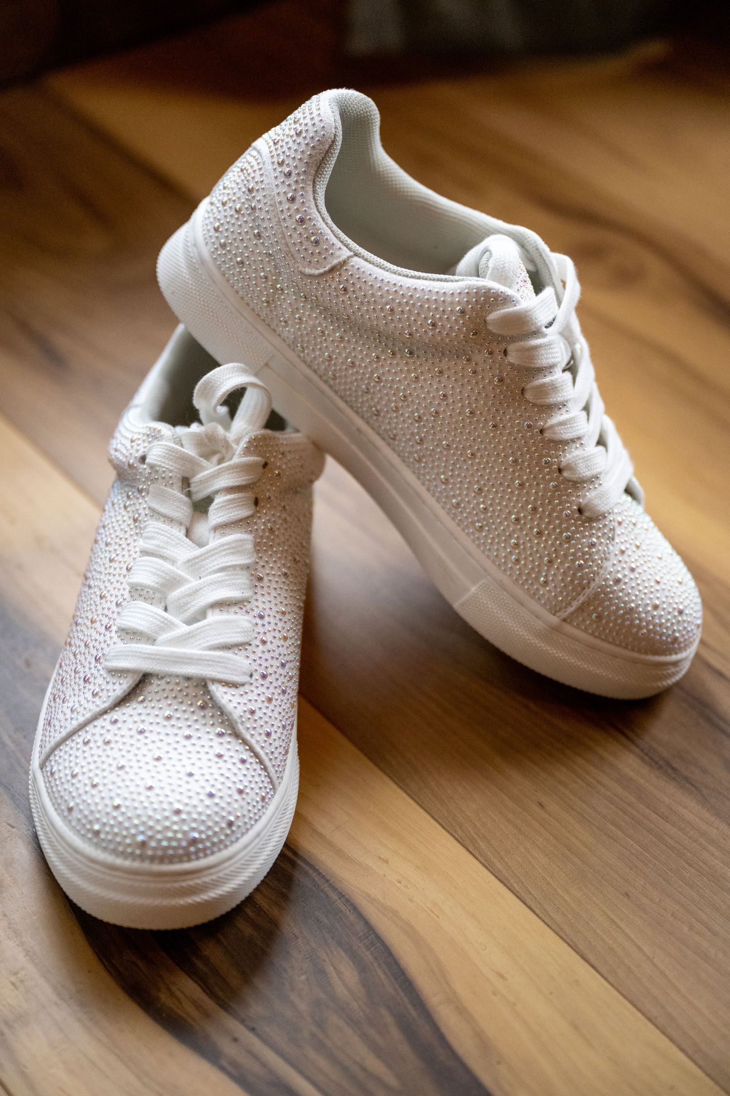 An oregon bride's studded tennis shoes set on a hardwood floor
