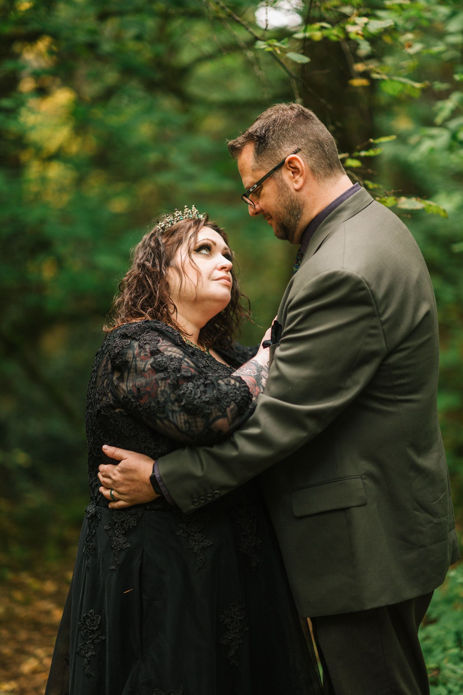 A couple embraces intimately outdoors in a wooded setting during autumn.