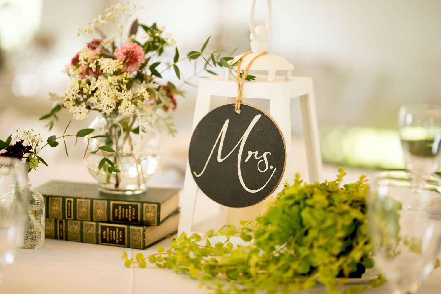 Wedding reception table decorations featuring delicate floral arrangements and vintage books.