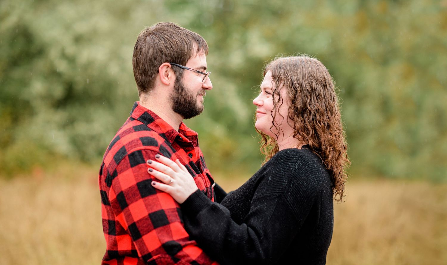 A couple embraces in casual outdoor portraits with autumn foliage in the background.