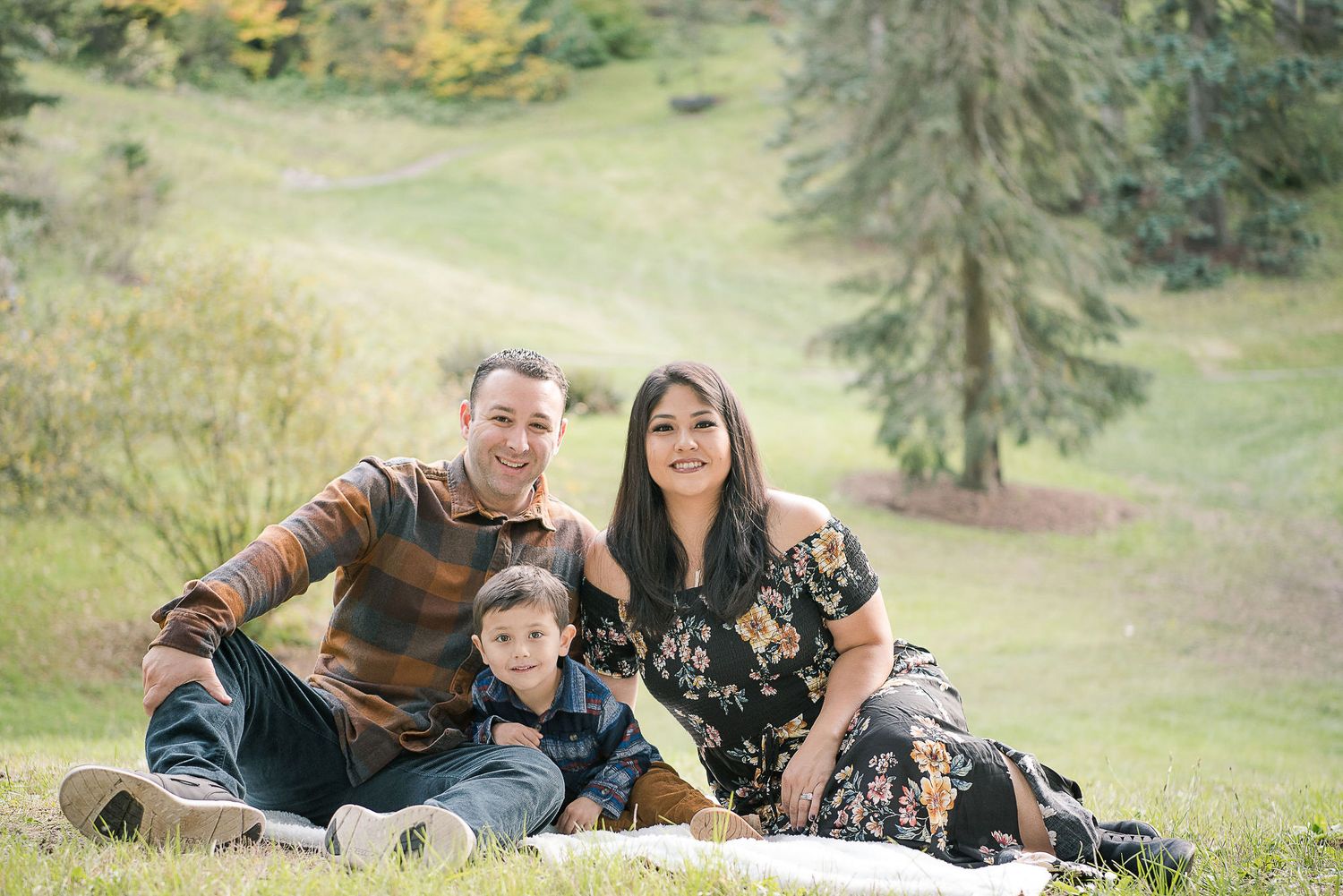 A family relaxes together on grass during an outdoor autumn photoshoot.