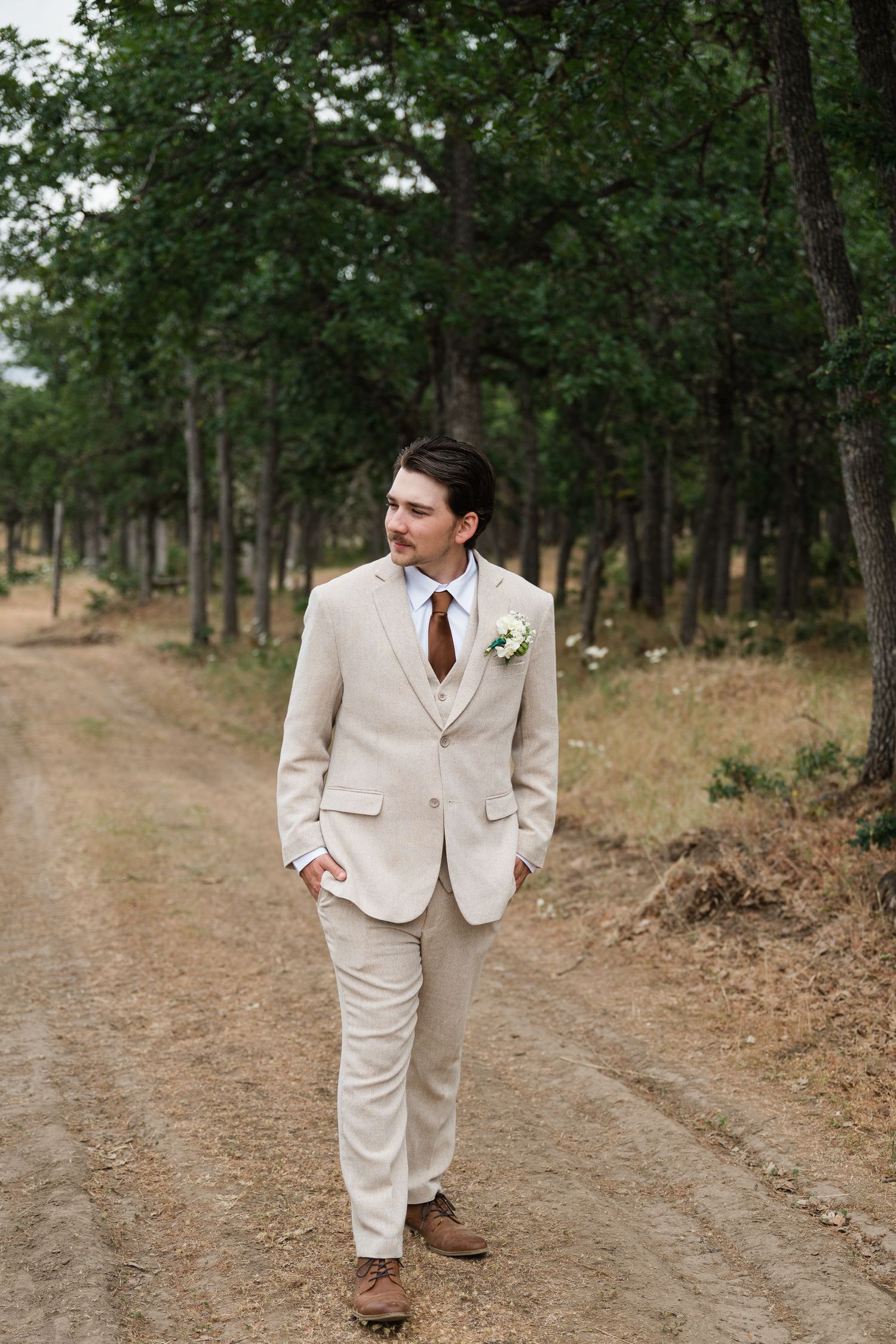 An oregon groom walks among the trees before his wedding ceremony in the dalles, oregon