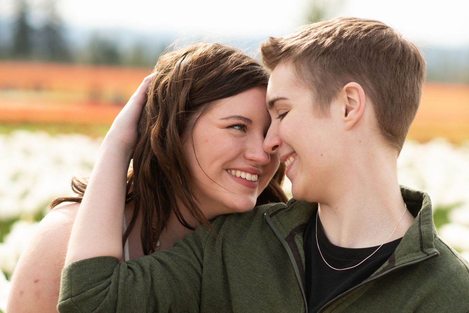 Intimate portrait of couple touching foreheads in flower field.