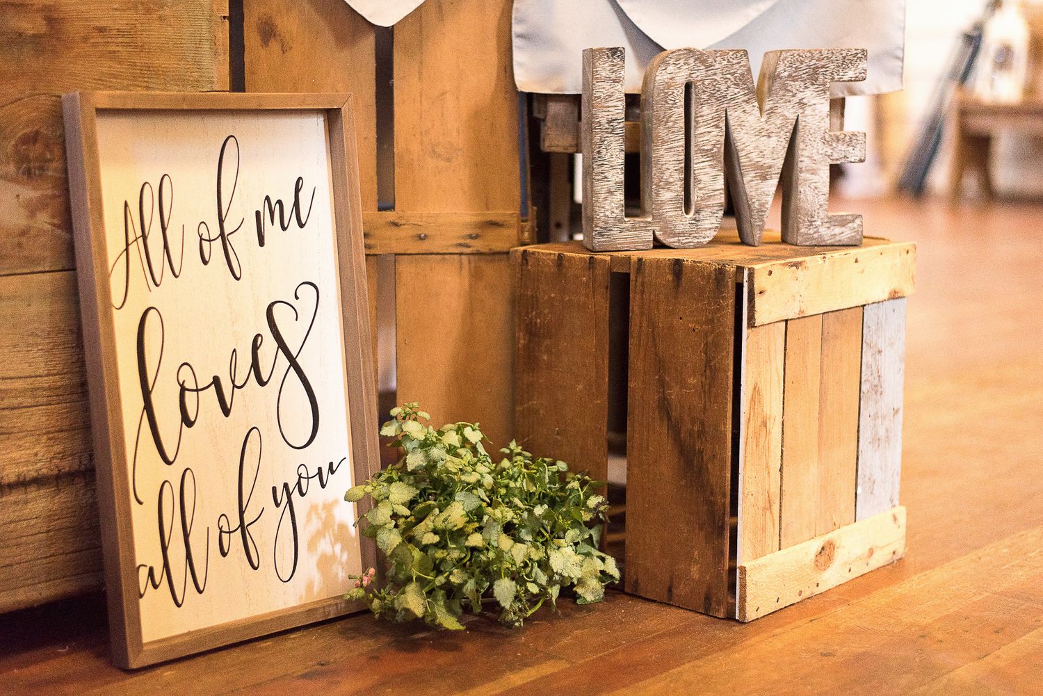 Rustic wooden wedding decor signs displayed against a barn wall.
