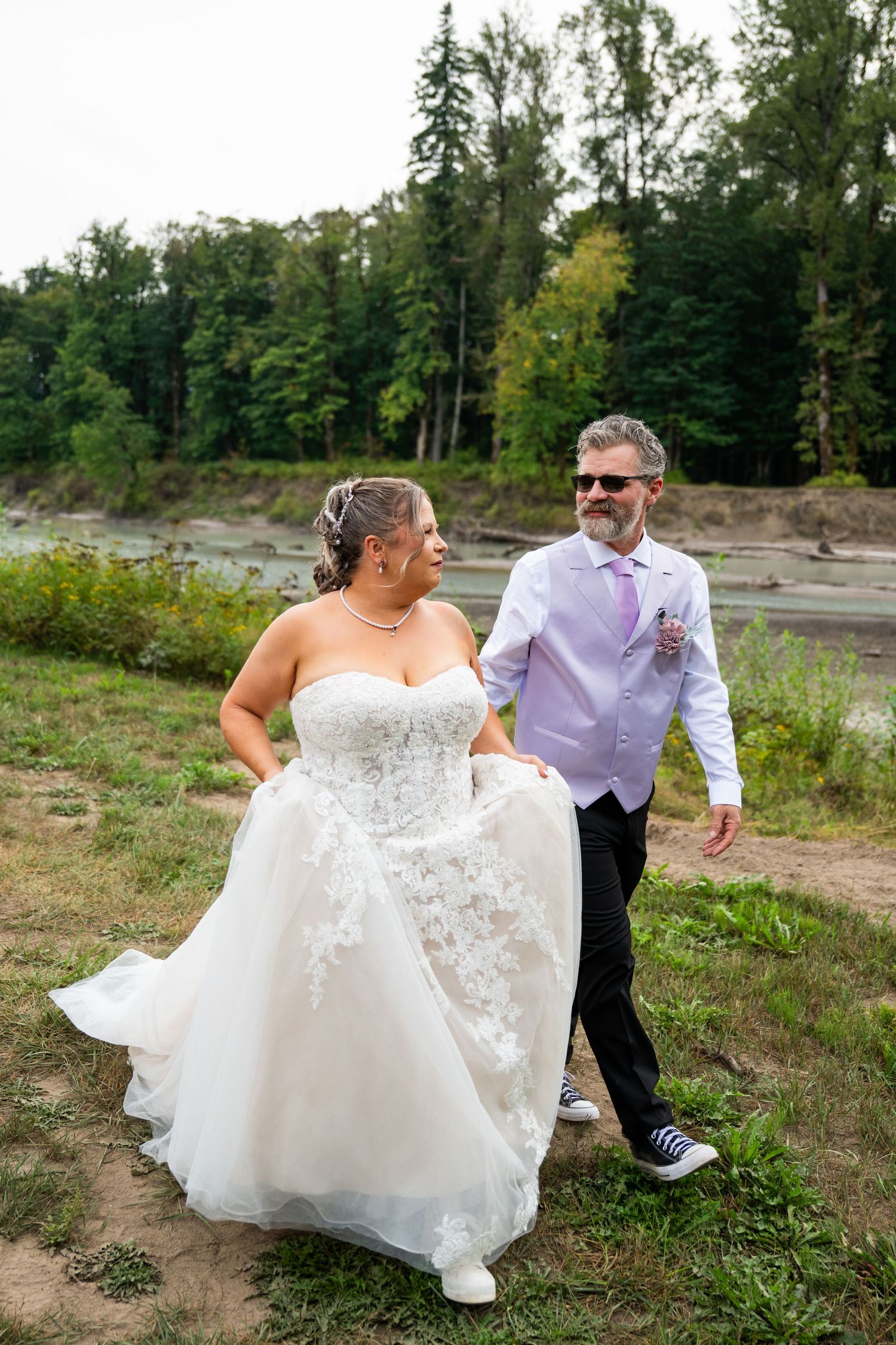 A couple dances together in a grassy field during their wedding photoshoot.