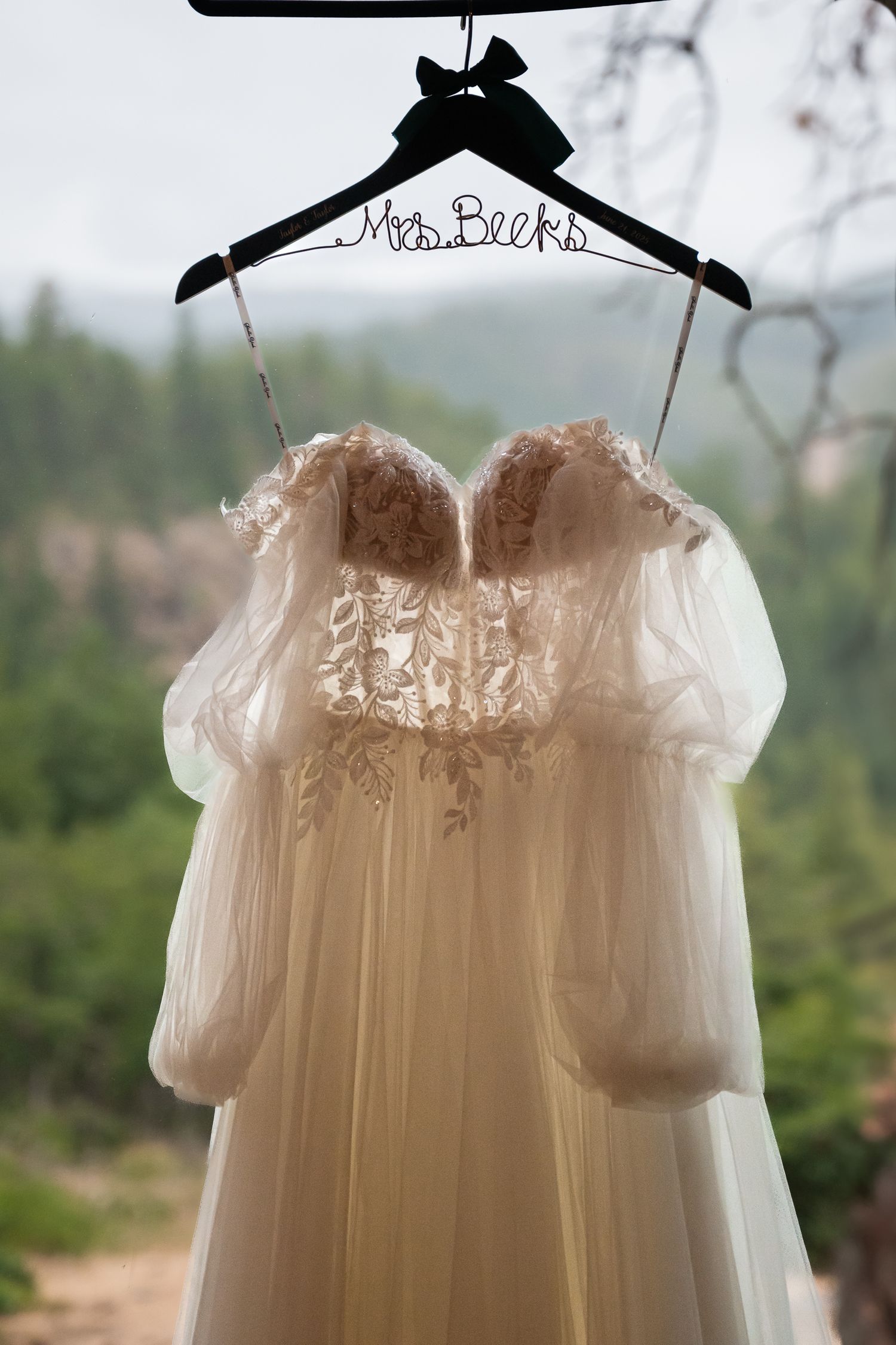 Strapless lace and tulle wedding gown hanging on a personalized Mrs. Beeks hanger with mountain backdrop.