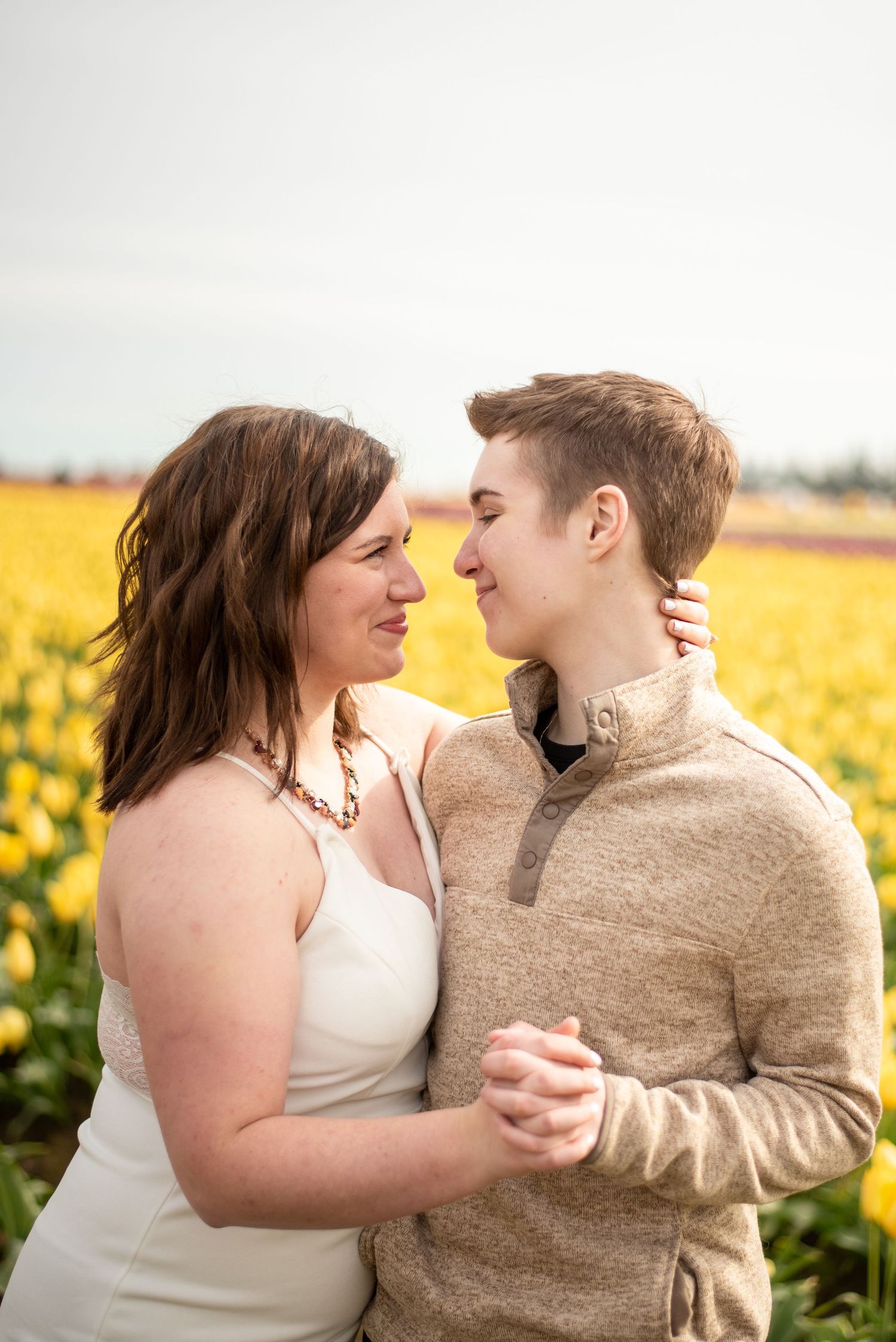 Romantic couple embraces in a field of vibrant yellow flowers.